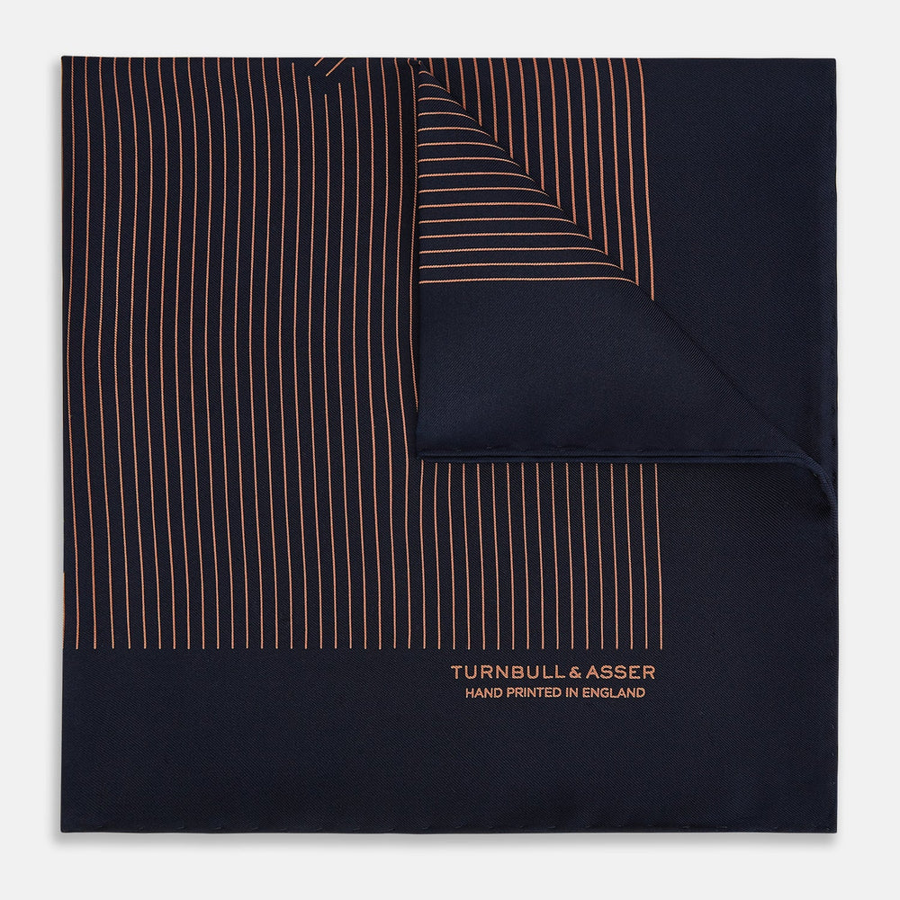 The Turnbull & Asser Navy and Blush Stripe Silk Pocket Square features thin blush stripes on navy silk, finished with "TURNBULL & ASSER HAND PRINTED IN ENGLAND" in the corner, highlighting its refined English craftsmanship.