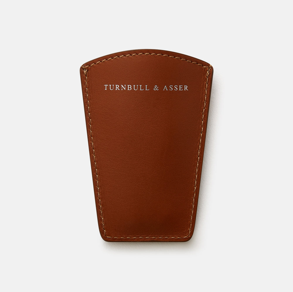 The Turnbull & Asser Camel Travel Shoe Horn features a wide, shiny silver blade and a brown Italian leather handle, displayed on a plain light background.