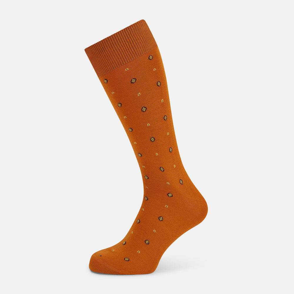 Turnbull & Asser’s Orange Patterned Mid-Length Socks, made from soft Egyptian cotton and featuring a ribbed cuff with small black and yellow geometric dots, are displayed against a plain white background.