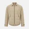 View 1 of product The Battersea Sand Quilted Jacket by Turnbull & Asser is a light beige men's jacket with a front zipper, pointed collar, zippered side pockets, chest pocket, and buttoned cuffs, shown on a plain white background.