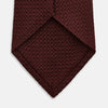 View 4 of product The Turnbull & Asser Ruby Red Knitted Tie, shown rolled-up against a white background, is a textured silk accessory that adds versatile sophistication to any gentleman's wardrobe.