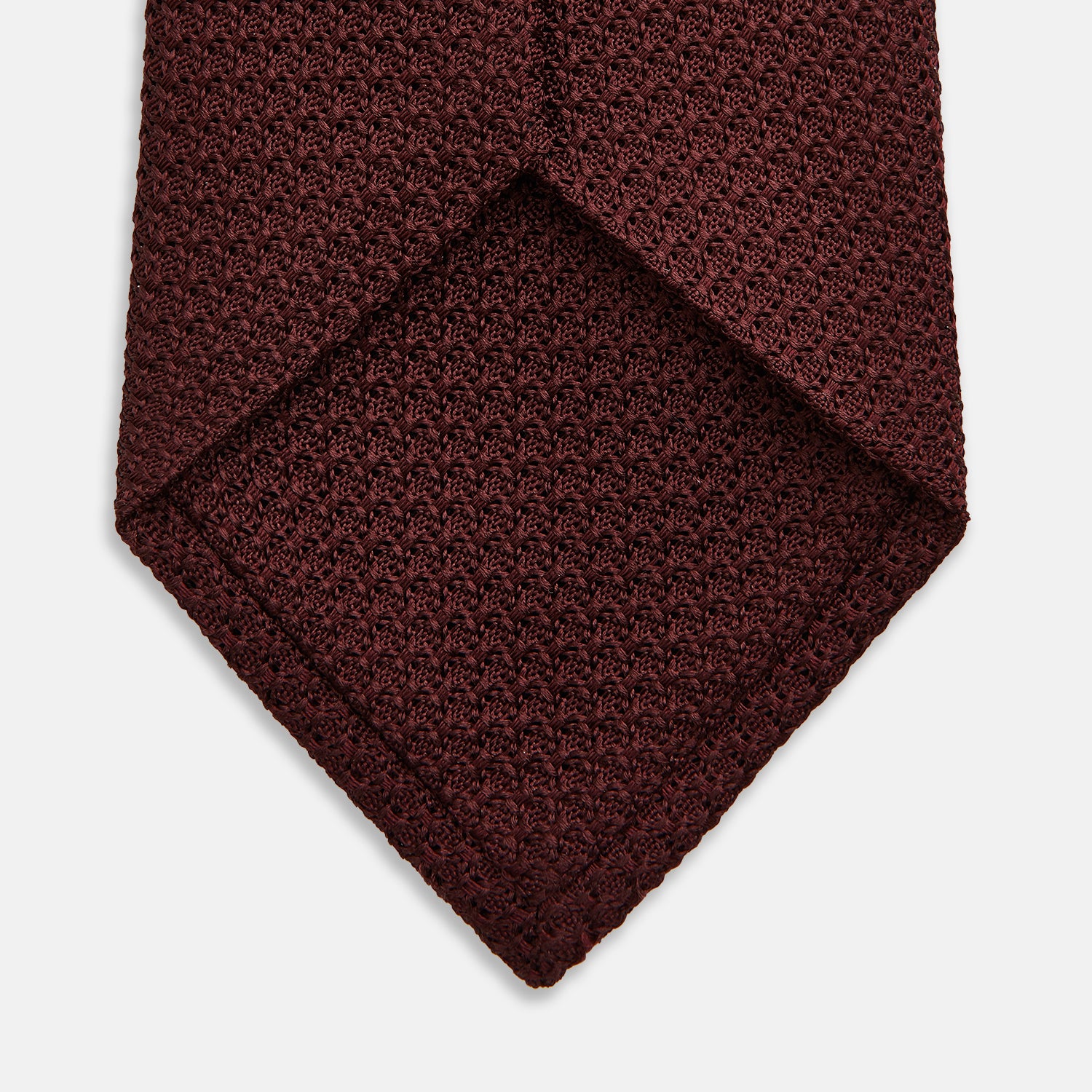 View 4 of product The Turnbull & Asser Ruby Red Knitted Tie, shown rolled-up against a white background, is a textured silk accessory that adds versatile sophistication to any gentleman's wardrobe.