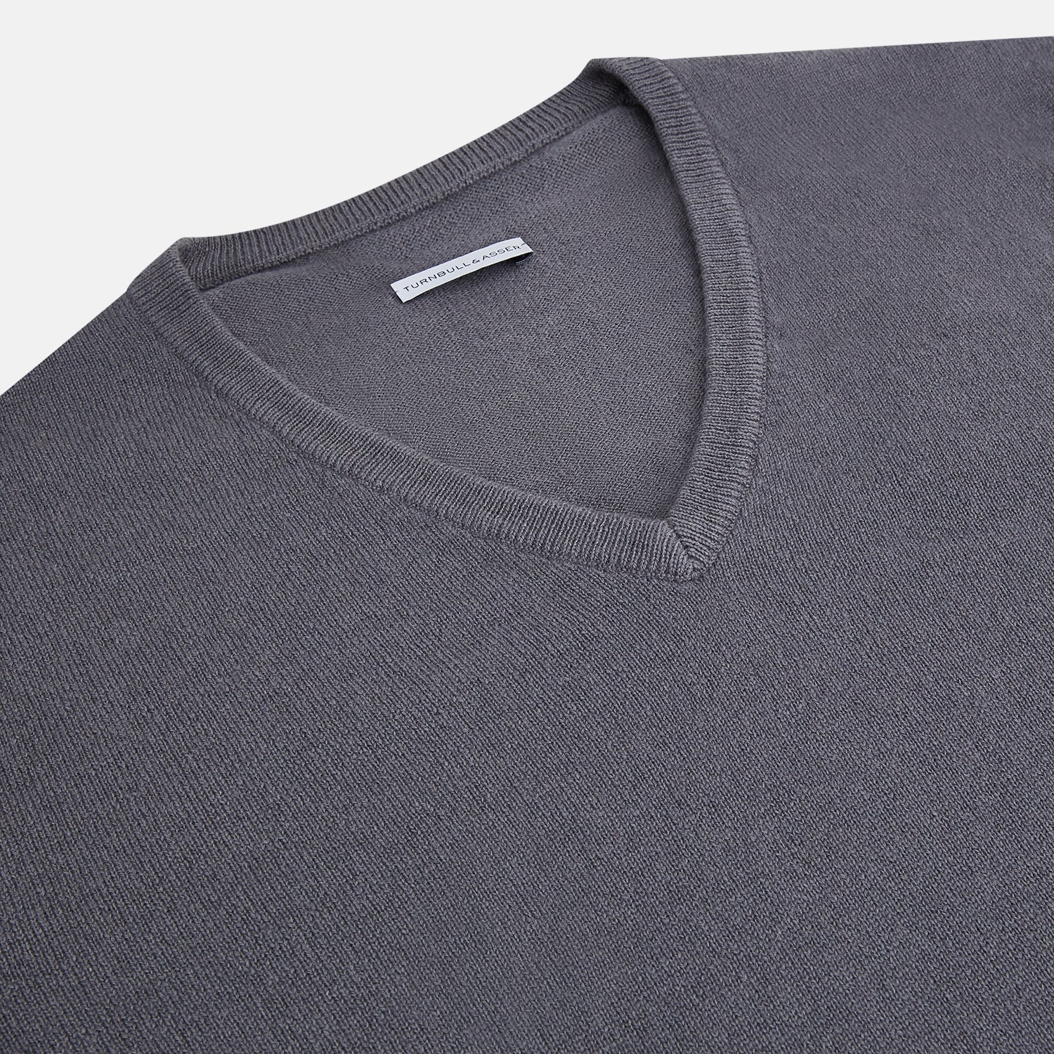 View 2 of product The Grey V-Neck Cashmere Jumper by Turnbull & Asser features long sleeves, ribbed cuffs and hem, in dark gray cashmere, shown against a white background.