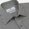 View 3 of product A person with a shaved head models the Turnbull & Asser Grey Check Weekend Fit Flannel Shirt with a Derby collar and 1-button cuffs, sleeves rolled up, paired with dark trousers against a plain background, gazing directly at the camera.