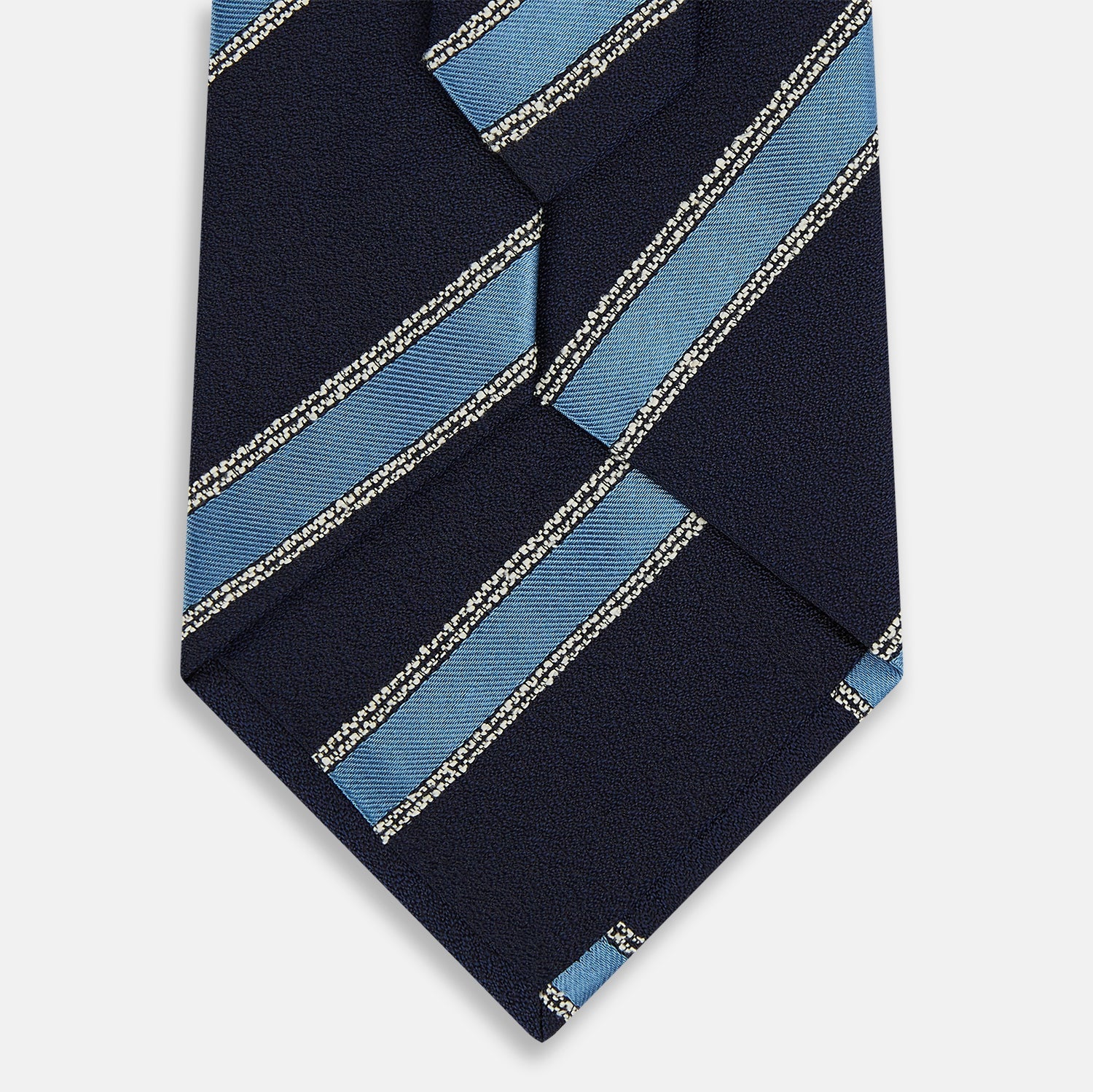 View 3 of product The Turnbull & Asser Navy Multi Stripe Silk Tie features diagonal light blue and silver stripes on an English silk navy base, rolled neatly against a white background.