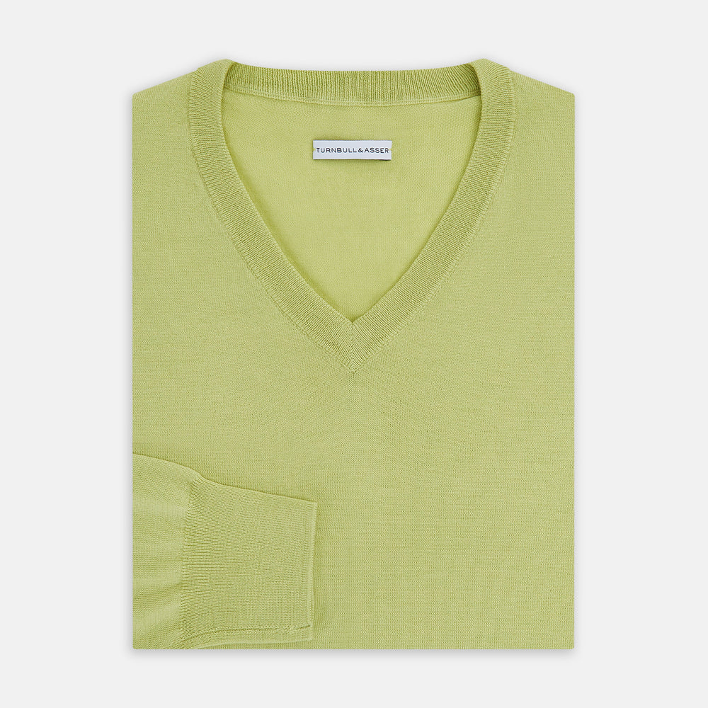 The Turnbull & Asser Melon Green Merino V-Neck Jumper is shown on a white background, featuring long sleeves, ribbed cuffs, and a ribbed hem.