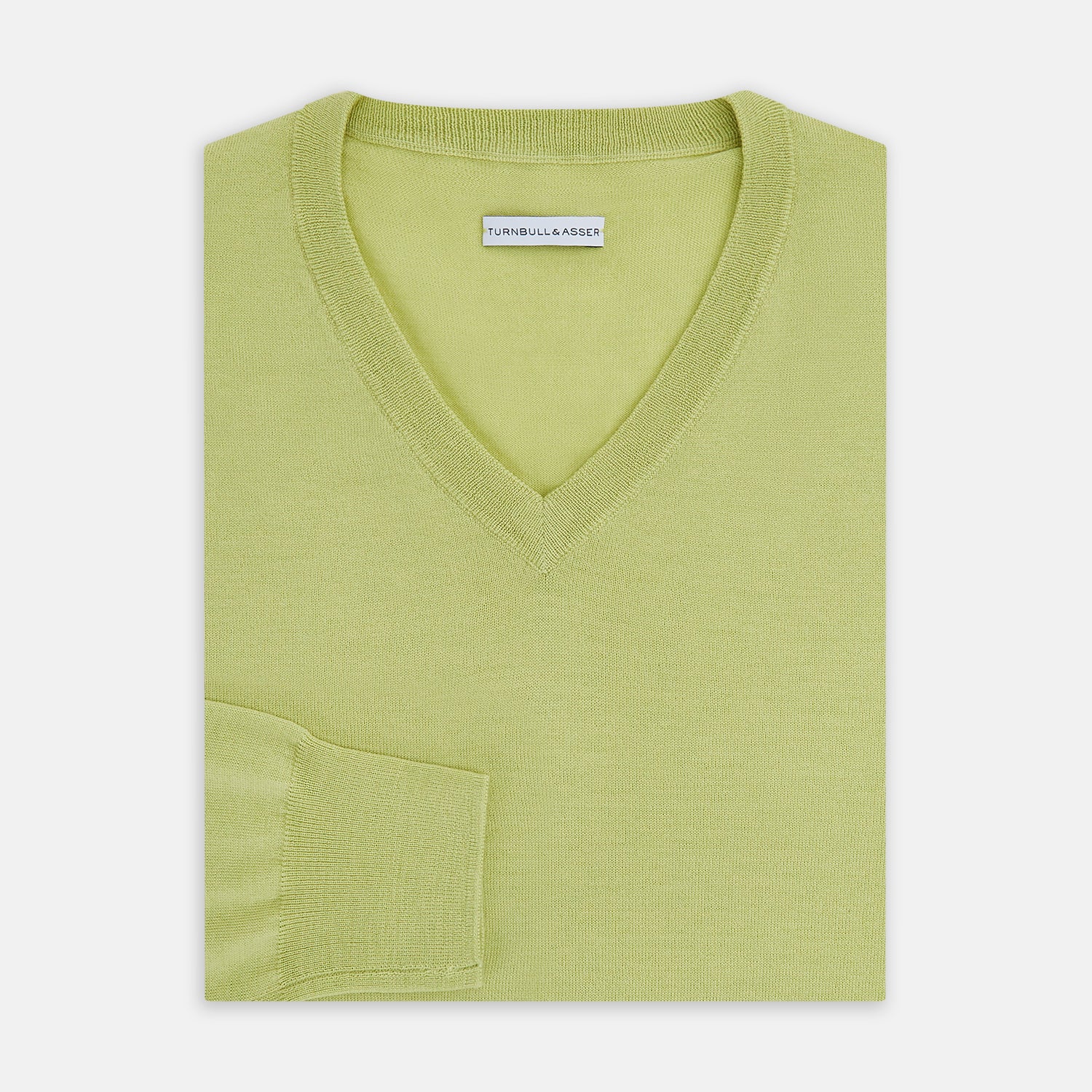 View 4 of product The Turnbull & Asser Melon Green Merino V-Neck Jumper is shown on a white background, featuring long sleeves, ribbed cuffs, and a ribbed hem.