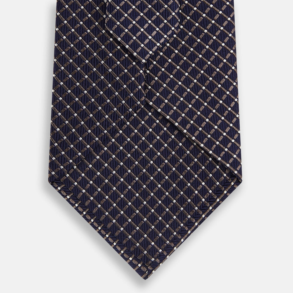 The Turnbull & Asser Silver and Navy Diamond Silk Tie features a neatly rolled silk design with a diagonal grid of small, light squares and lines, displayed on a plain background—perfect for an elegant, professional look.