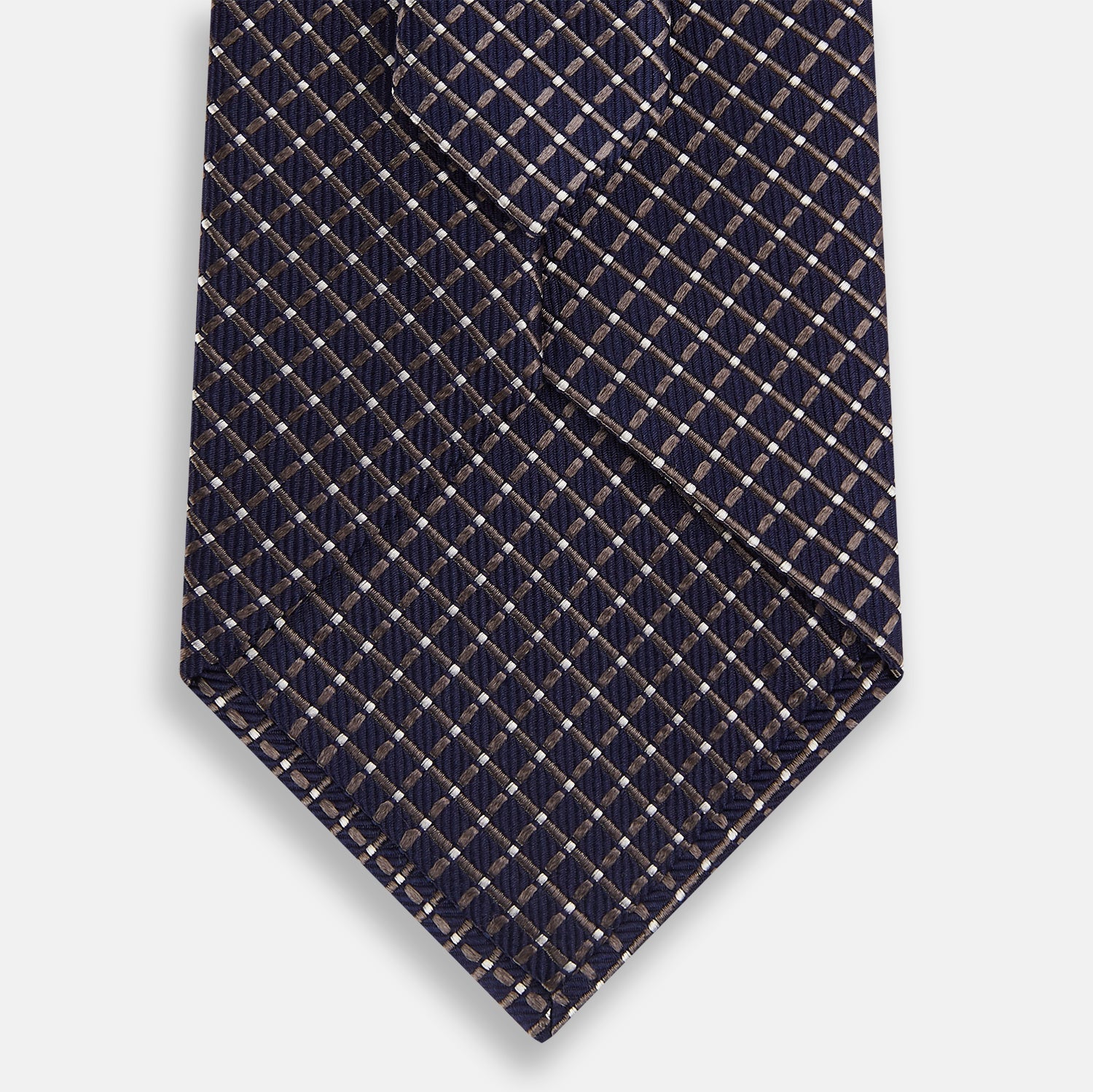 View 3 of product The Turnbull & Asser Silver and Navy Diamond Silk Tie features a neatly rolled silk design with a diagonal grid of small, light squares and lines, displayed on a plain background—perfect for an elegant, professional look.
