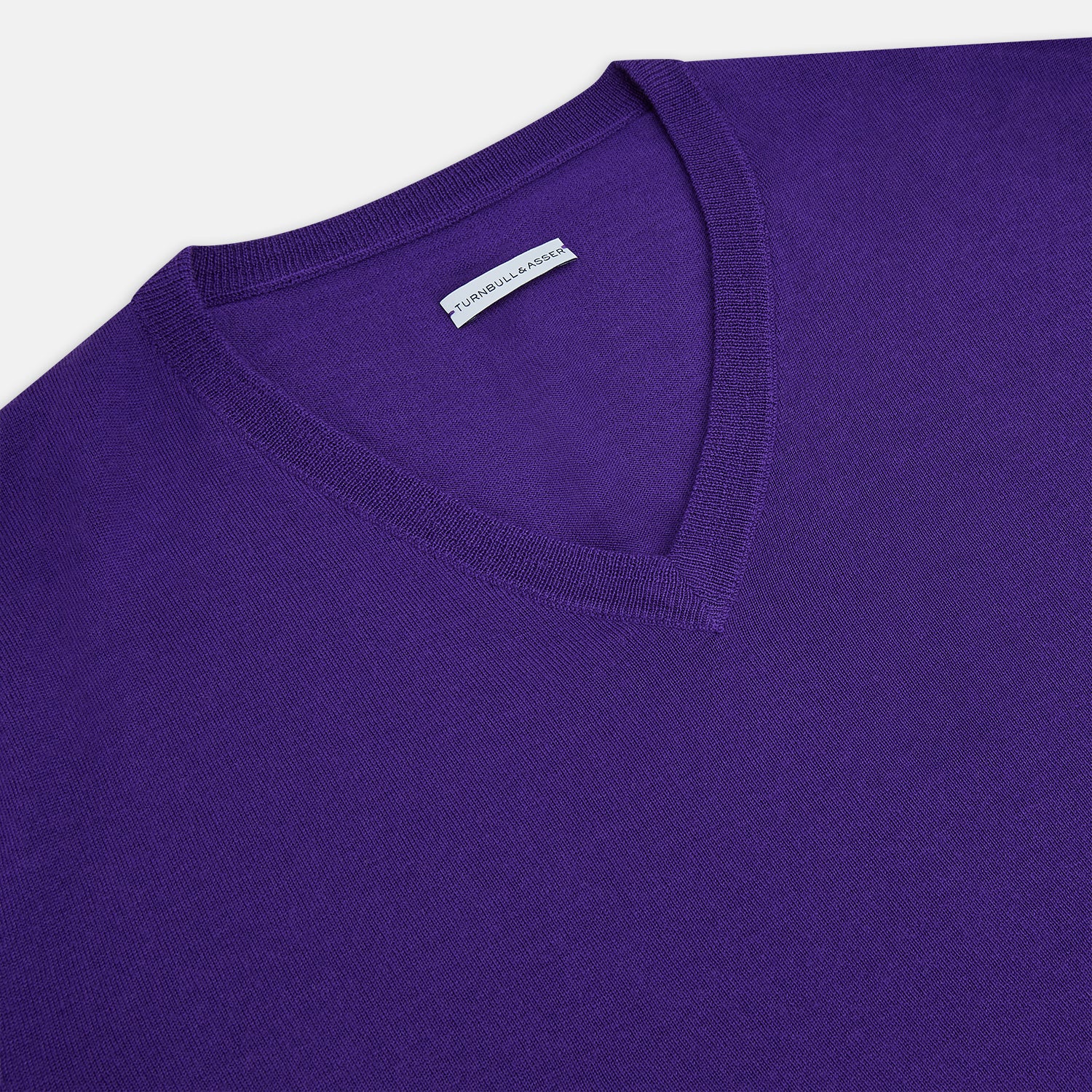 View 2 of product The Turnbull & Asser Purple Merino V-Neck Jumper features long sleeves and a rich, solid hue, making it an essential knitwear piece for any wardrobe.