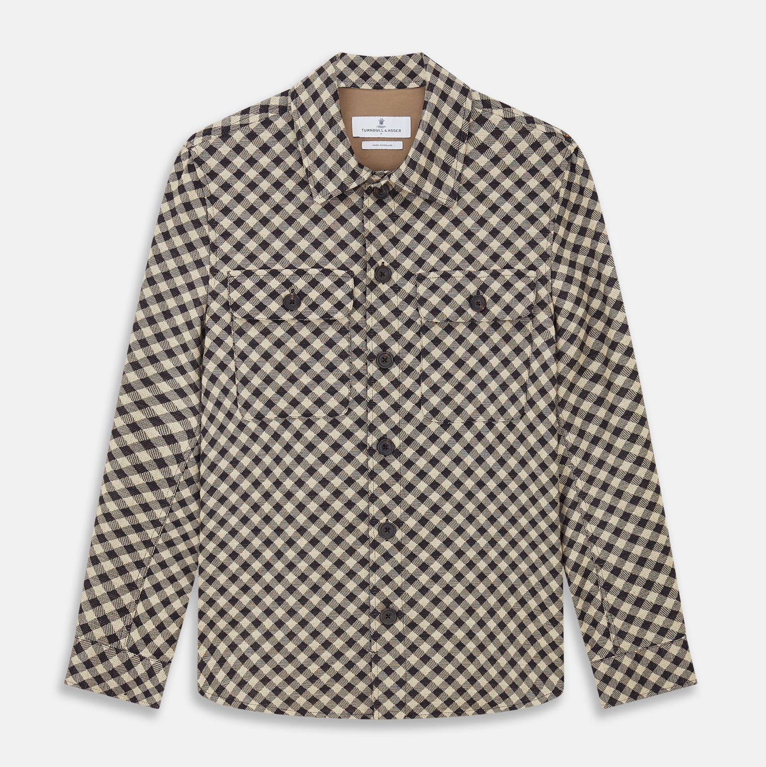 View 1 of product The Turnbull & Asser Black Gingham Check Wool Blend Somerset Overshirt features long sleeves, two chest flap pockets with buttons, and a black-and-beige check pattern. Shown laid flat on a white background; ideal as transitional outerwear.