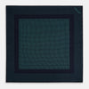 View 3 of product The Turnbull & Asser Navy and Petrol Green Dot Silk Pocket Square features handmade craftsmanship with petrol green polka dots and a darker border, elegantly displayed on a white background.