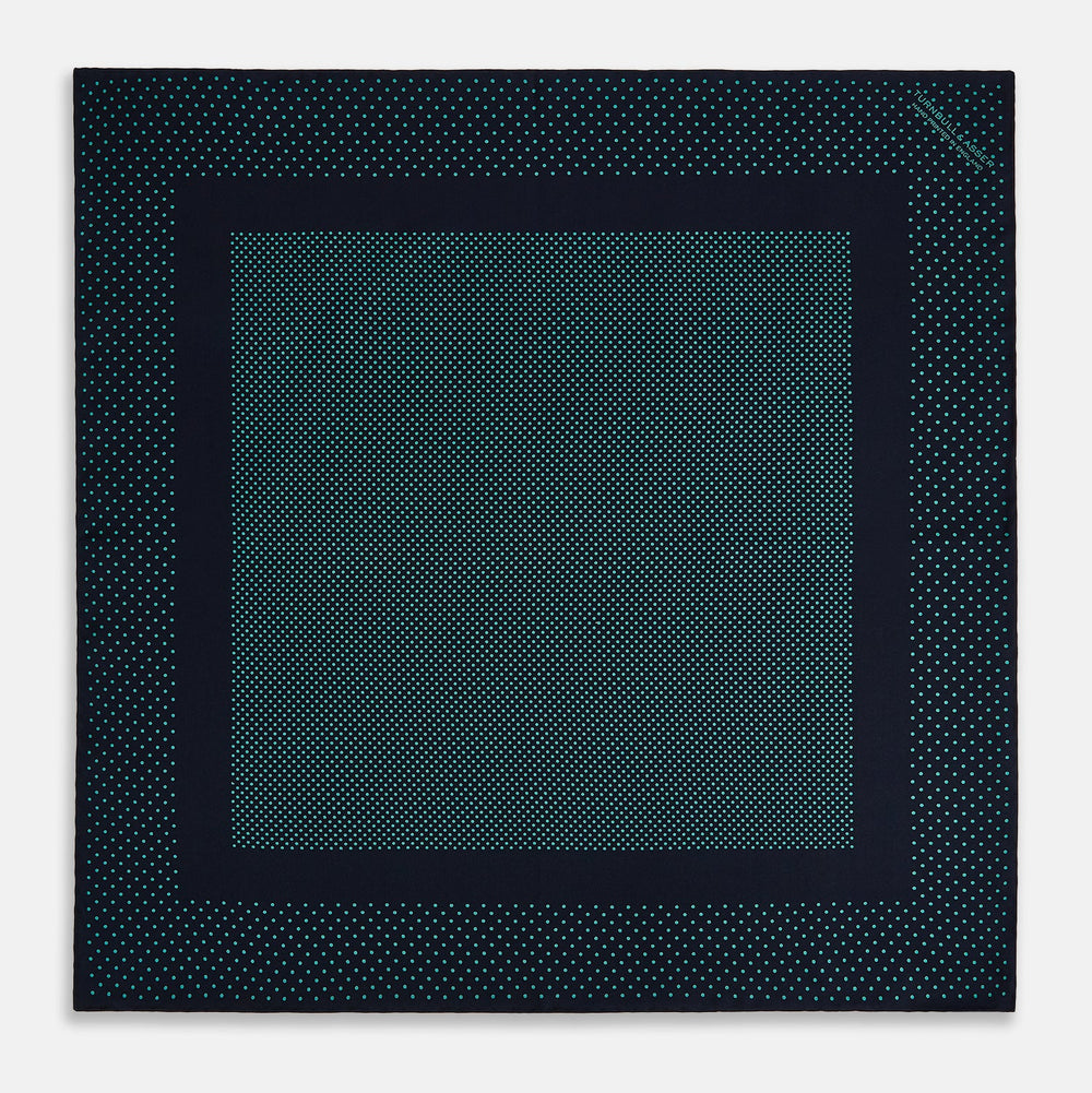 The Turnbull & Asser Navy and Petrol Green Dot Silk Pocket Square features handmade craftsmanship with petrol green polka dots and a darker border, elegantly displayed on a white background.