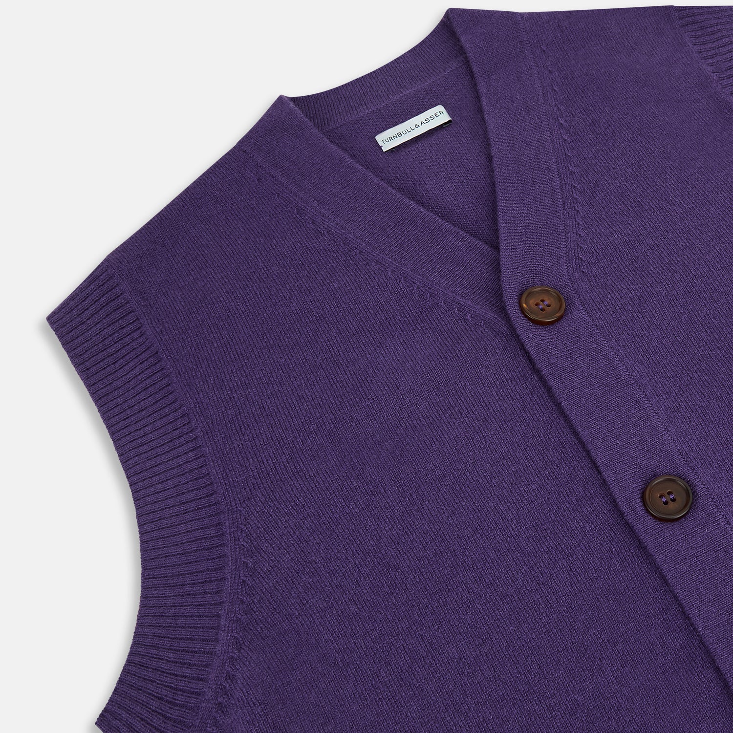 View 2 of product The Turnbull & Asser Purple Cashmere Sleeveless Cardigan features a V-neck, brown buttons, front pockets, and ribbed trim—an elegant, lightweight layer shown against a plain white background.
