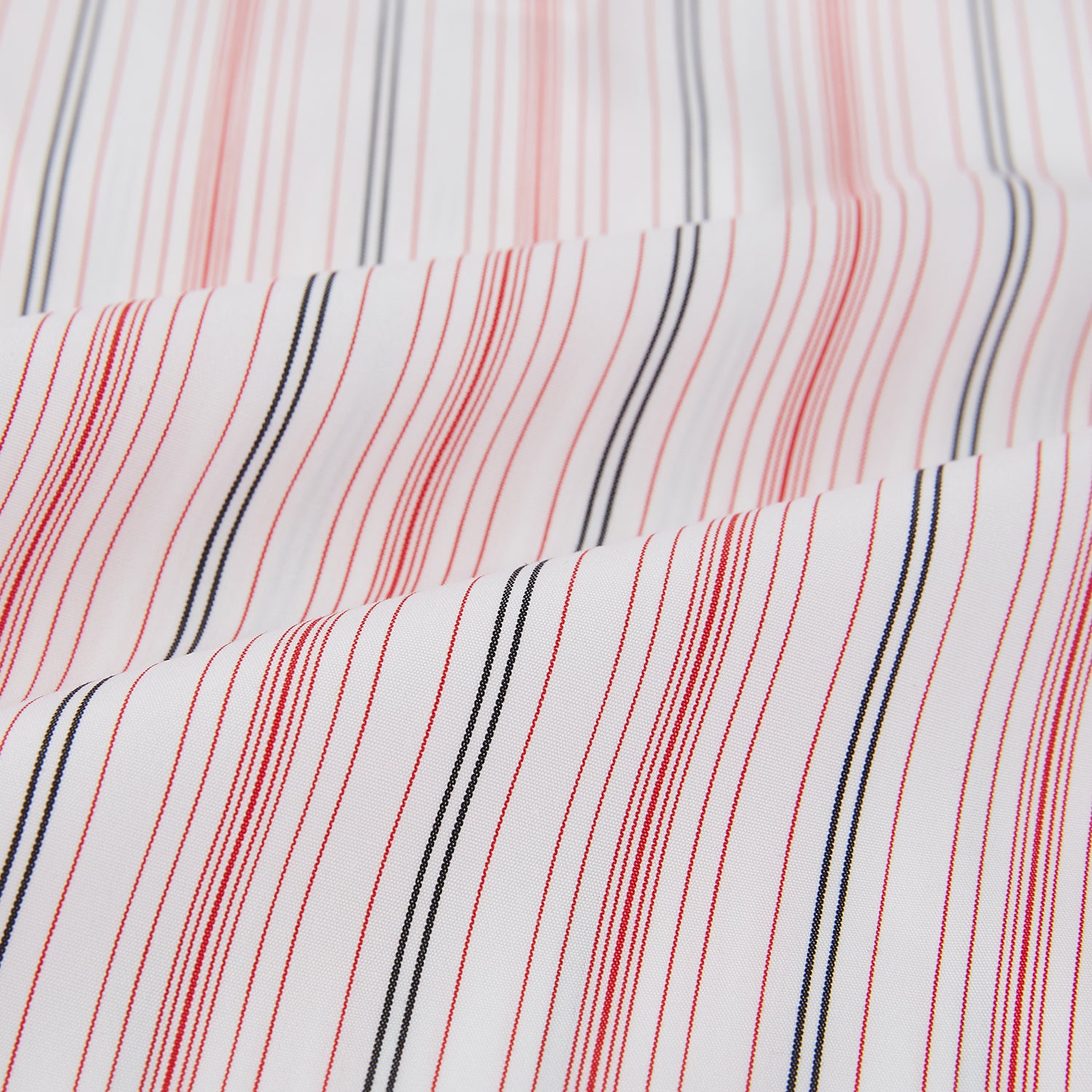 View 8 of product The Red Multi Pencil Stripe Windsor Shirt by Turnbull & Asser features long sleeves, buttoned cuffs, a Turnbull collar, and classic British tailoring with vertical red, pink, and white stripes.