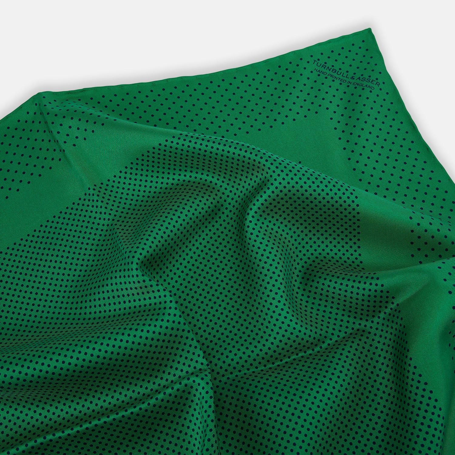 View 2 of product The Turnbull & Asser Green Dot Silk Pocket Square is handmade in England and shown neatly folded, revealing the front and part of the underside against a white background.