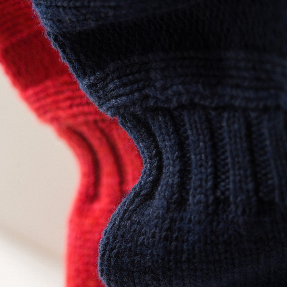 The Red Lewis Guernsey Knitted Jumper by Turnbull & Asser is a bright red wool-cotton, long-sleeve jumper with a round neckline, ribbed cuffs, and ribbed hem, shown against a white background.