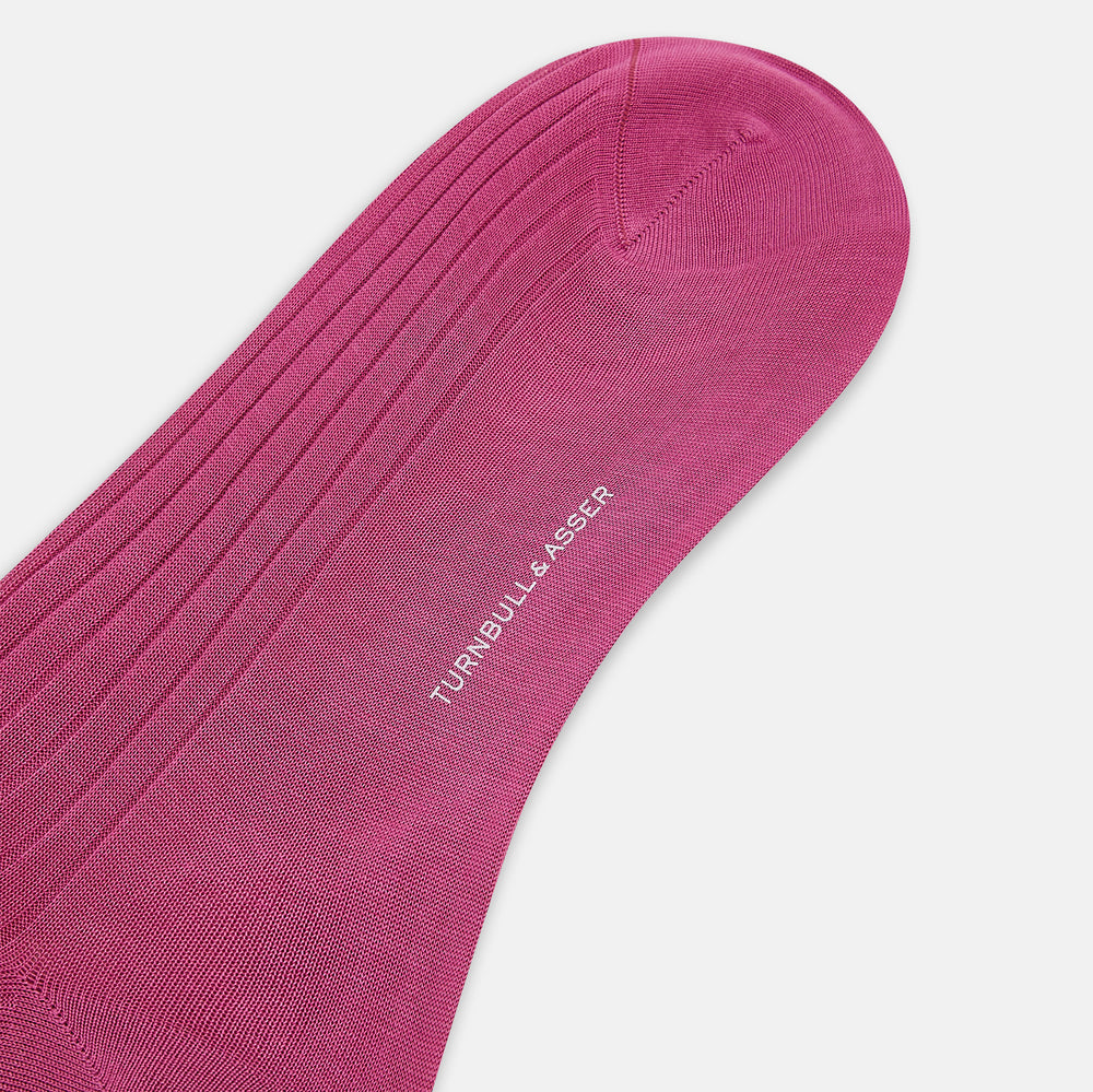 A single Turnbull & Asser Pink Mid-Length Sock is shown upright on a plain white background. The luxury sock has a ribbed texture and a subtly darker ribbed cuff at the top, creating an elegant finish.