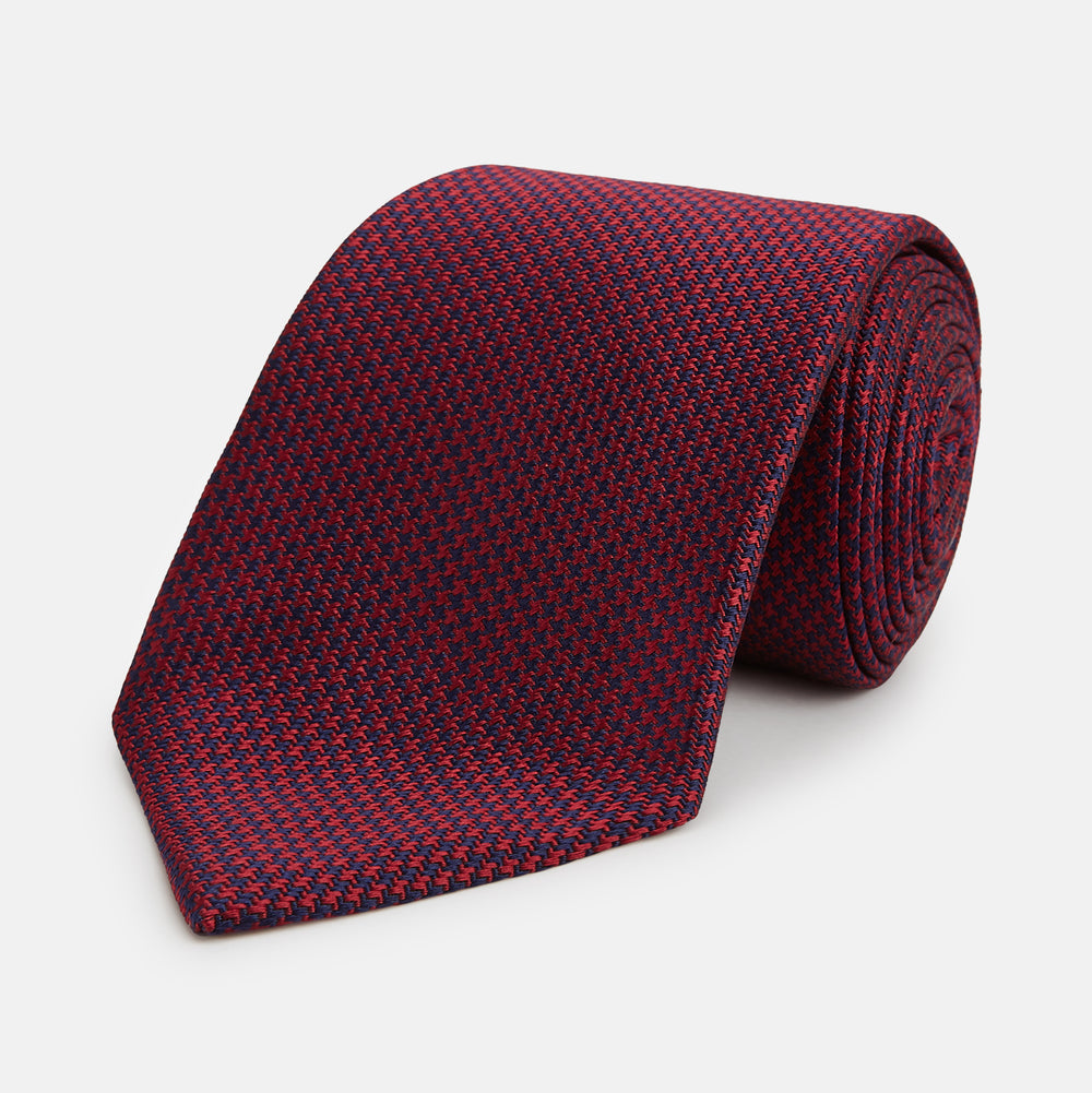 The HOUNDSTOOTH NAVY BURGUNDY TIE by Turnbull & Asser features a textured navy and burgundy silk woven pattern—an elegant staple for every gentleman’s wardrobe.