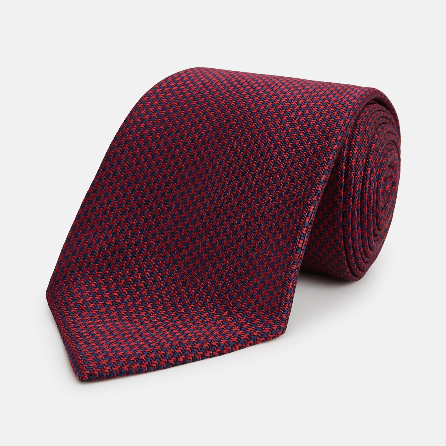 View 1 of product The HOUNDSTOOTH NAVY BURGUNDY TIE by Turnbull & Asser features a textured navy and burgundy silk woven pattern—an elegant staple for every gentleman’s wardrobe.