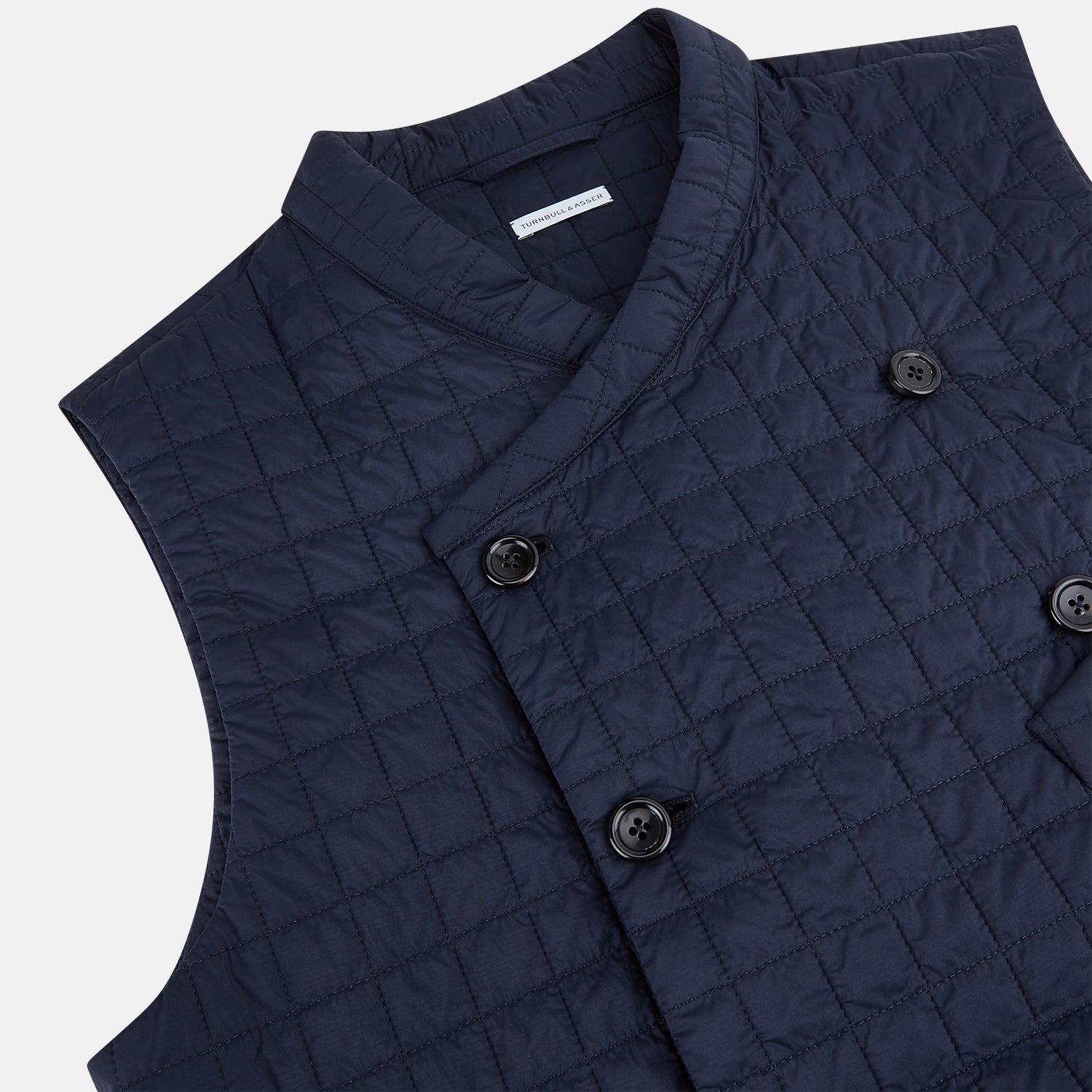 View 2 of product The Turnbull & Asser Navy Double-Breasted Quilted Gilet is a sleeveless piece with an asymmetrical button closure, chest pocket, and two zippered side pockets, shown on a plain white background—ideal for layered dressing.