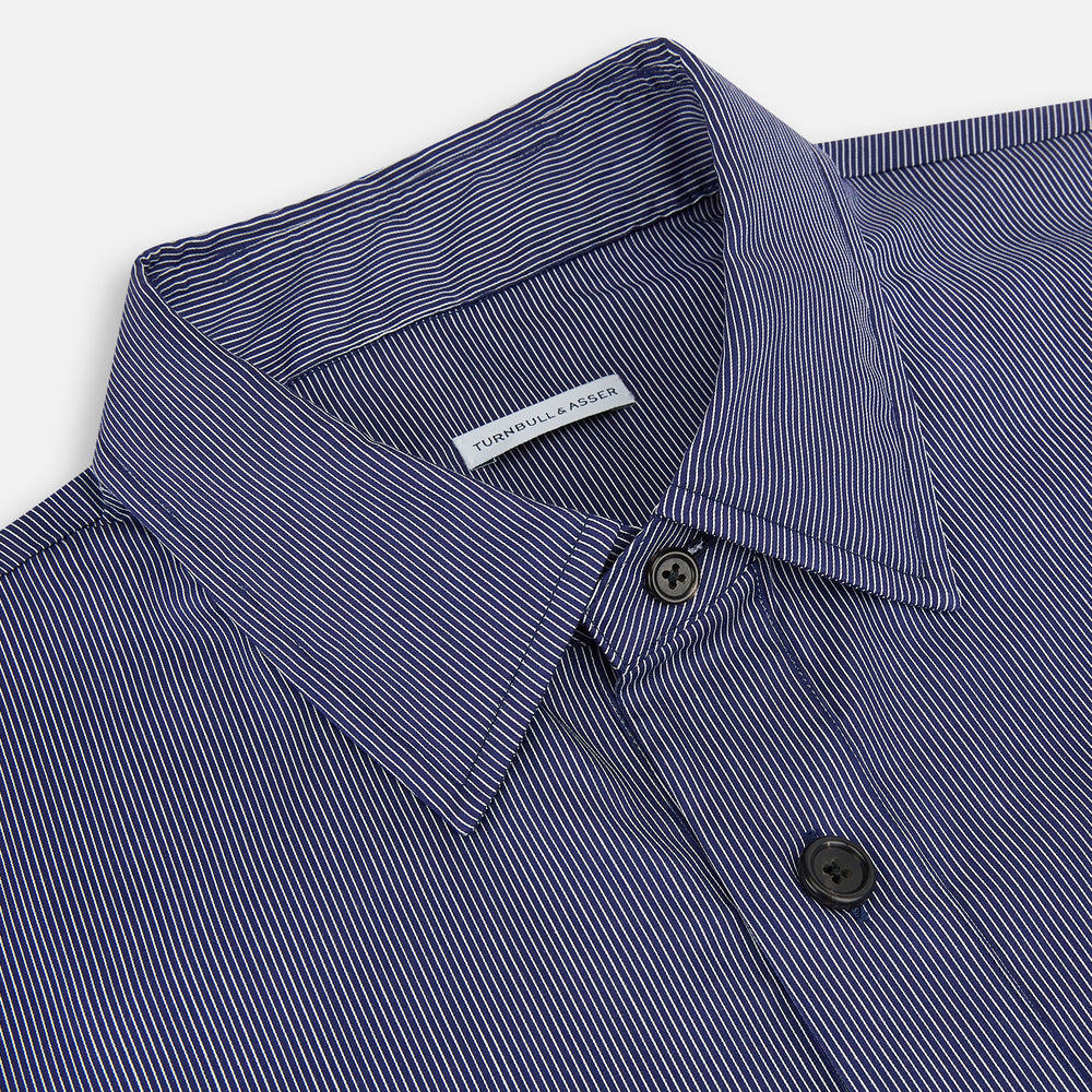 Turnbull & Asser’s Navy Stripe Highbury Overshirt with long sleeves, button-up front, black buttons, collar, and a left chest pocket is shown laid flat on a white background.