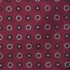 View 3 of product The Red Spheric Emblem Tie by Turnbull & Asser is a rolled-up maroon silk tie with a jacquard pattern of small white and purple circular dots, shown against a white background.