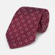 The Red Spheric Emblem Tie by Turnbull & Asser is a rolled-up maroon silk tie with a jacquard pattern of small white and purple circular dots, shown against a white background.