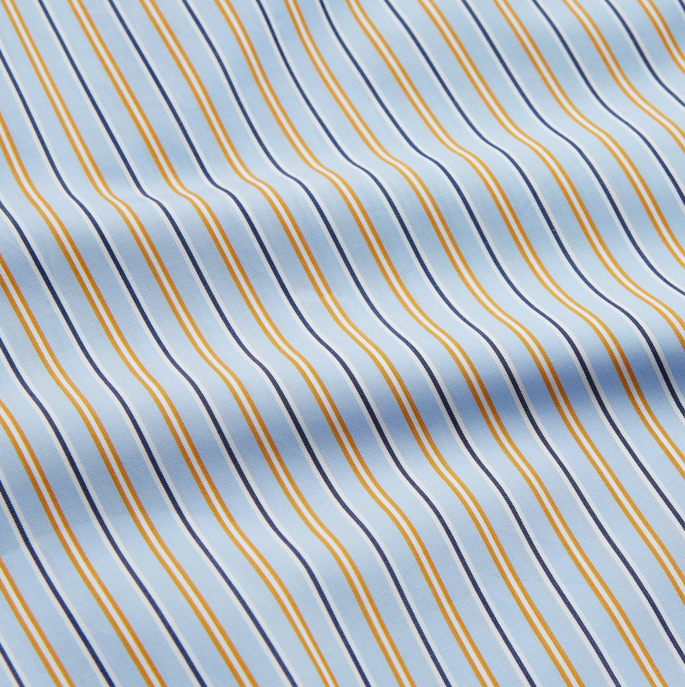 The Turnbull & Asser Blue, Orange and Navy Stripe Nightshirt is a loose-fitting shirt dress with vertical stripes, a pointed collar, chest pocket with blue trim, button-down front, long sleeves with cuffs, and a curved hem.