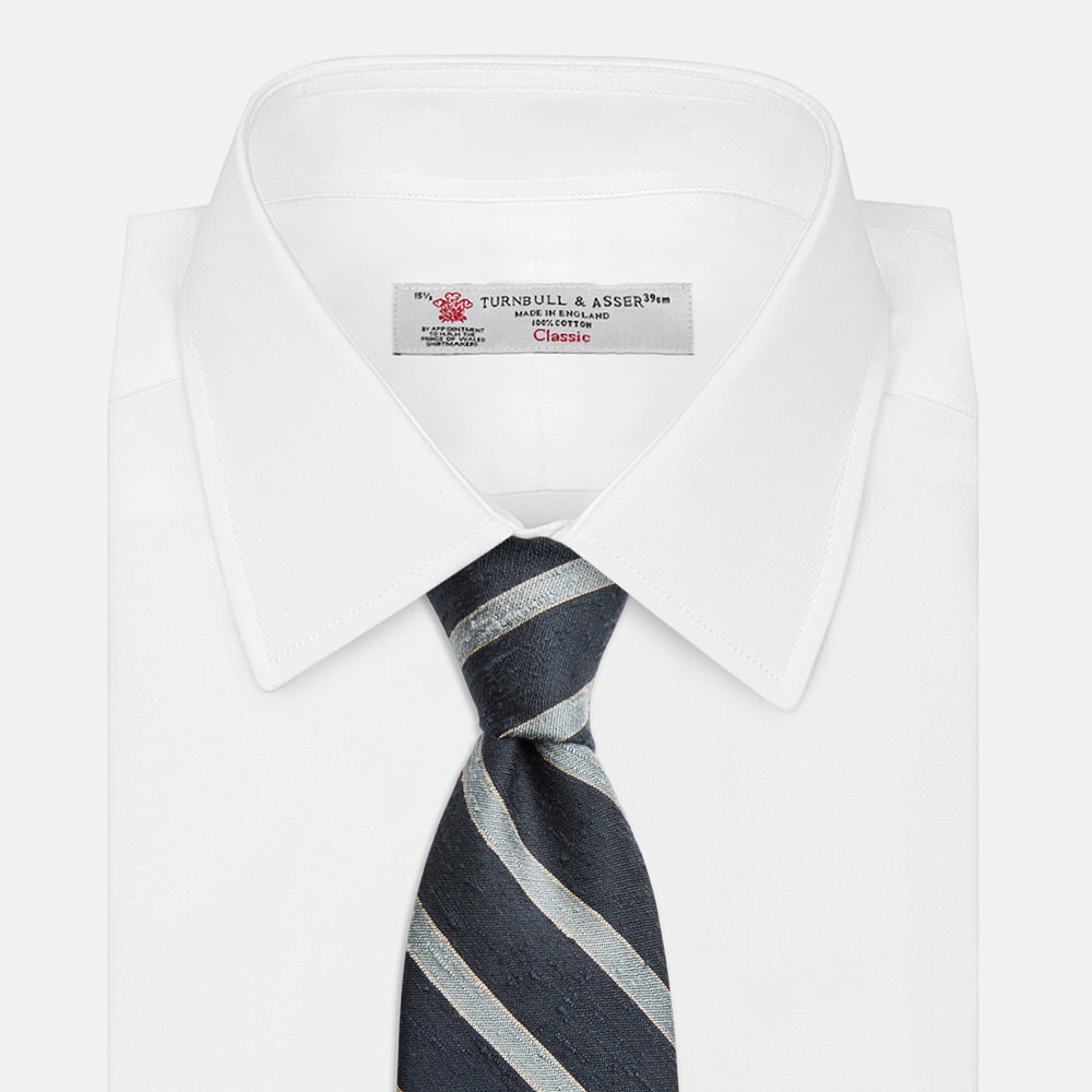 The Turnbull & Asser Blue & Silver Stripe Silk Tie, featuring wide diagonal stripes, is rolled up and displayed against a plain white background.