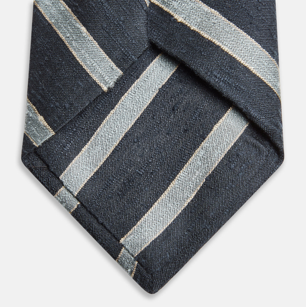 The Turnbull & Asser Blue & Silver Stripe Silk Tie, featuring wide diagonal stripes, is rolled up and displayed against a plain white background.