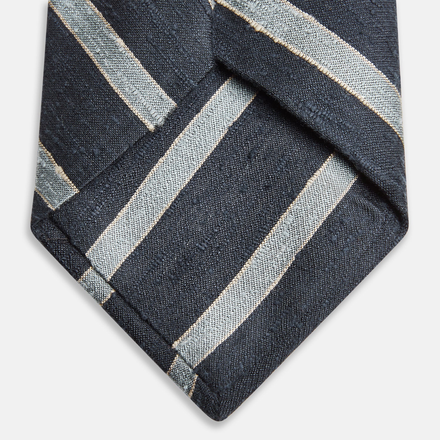 View 4 of product The Turnbull & Asser Blue & Silver Stripe Silk Tie, featuring wide diagonal stripes, is rolled up and displayed against a plain white background.
