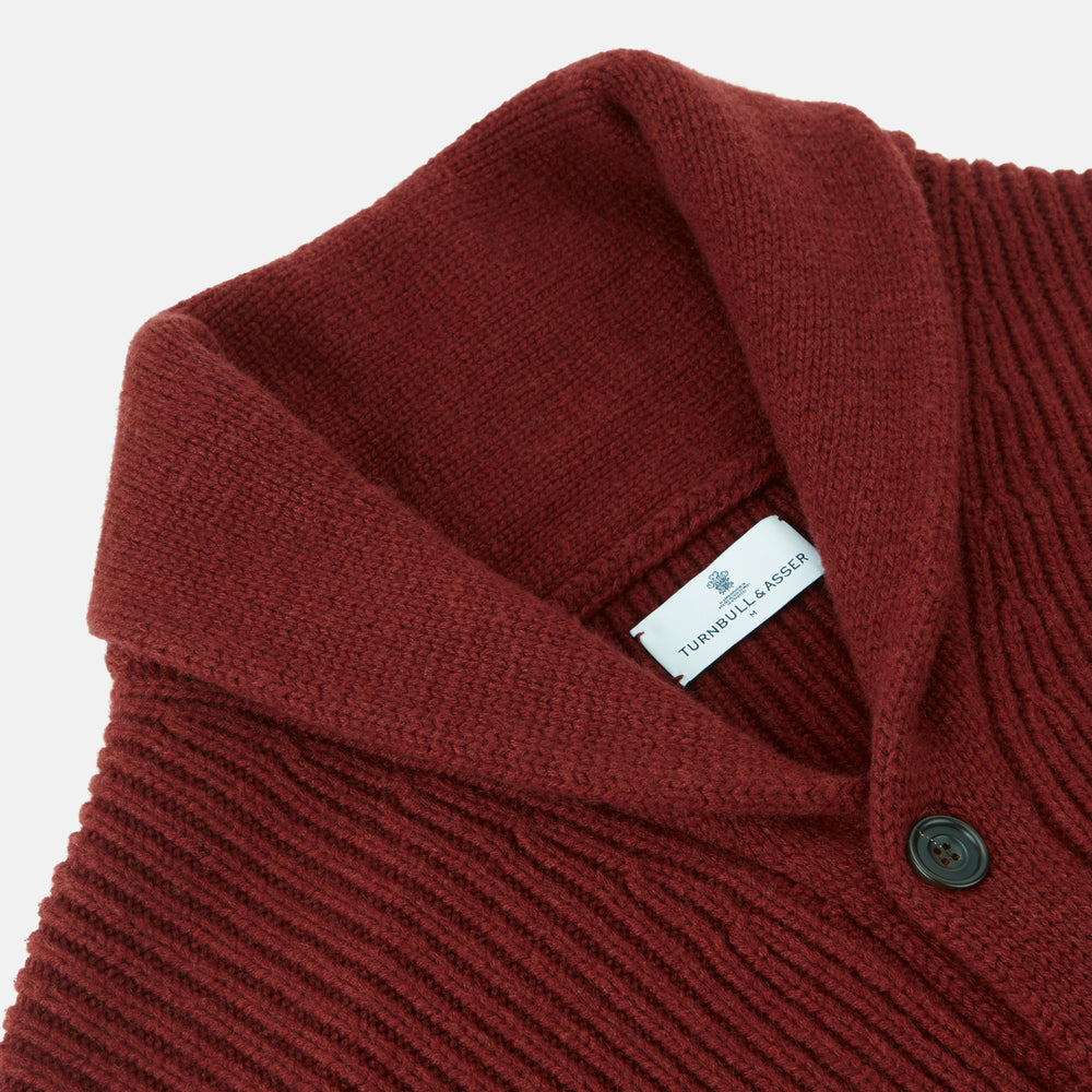 The Turnbull & Asser Burgundy Cashmere Ribbed Shawl Neck Ainsley Cardigan, featuring a button closure and two front pockets, is displayed flat on a white background.