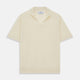 The Turnbull & Asser Ecru Merino Wool Roland Polo Shirt, made in Scotland, features soft merino wool, short sleeves, a relaxed open collar, and an inner neckline label. Shown here on a plain white background.