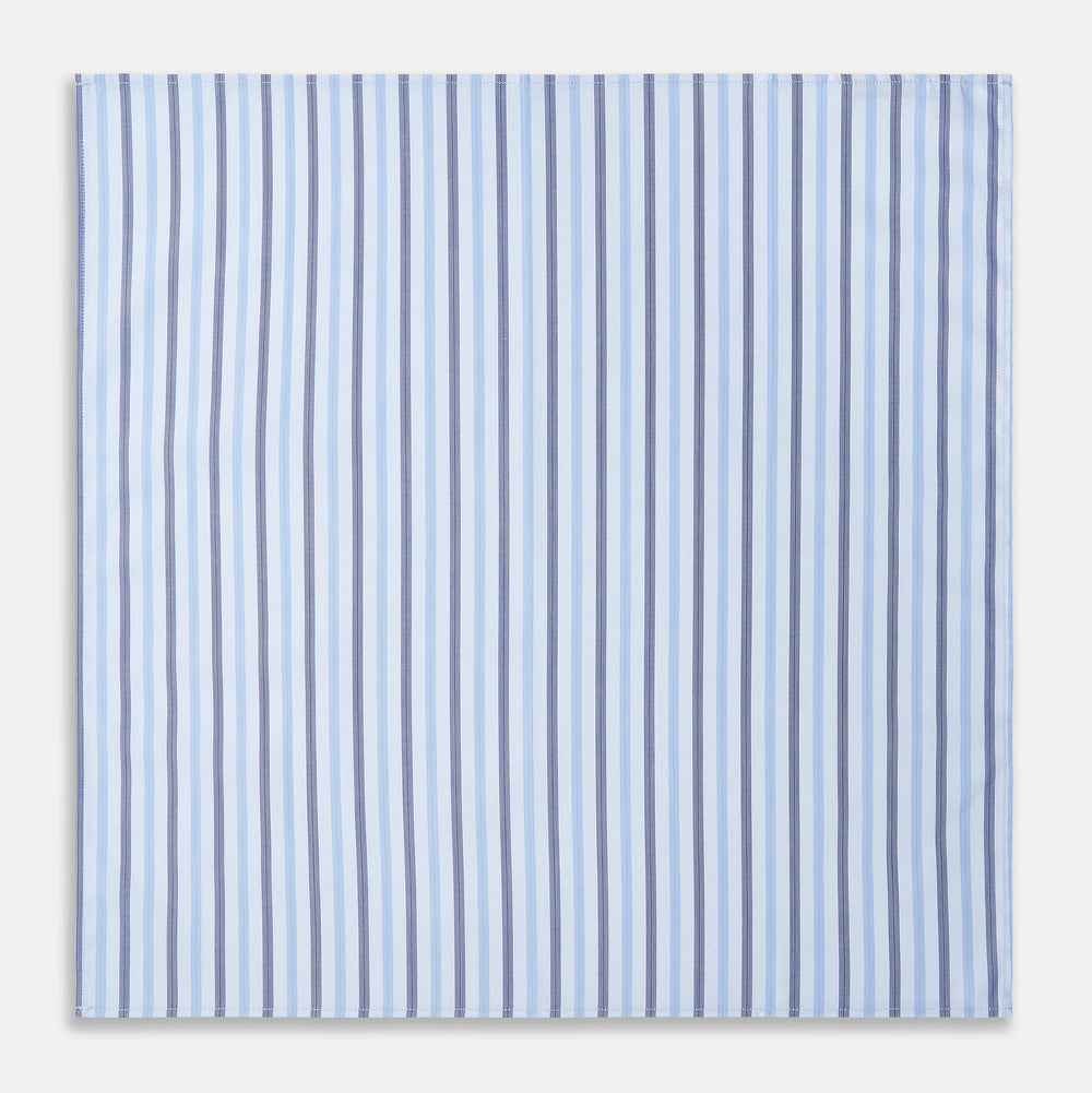 The Turnbull & Asser Blue Multi Stripe Cotton Handkerchief is shown flat against a white background, with one corner folded to reveal its reverse side. It features horizontal and vertical blue and white stripes on luxury cotton.