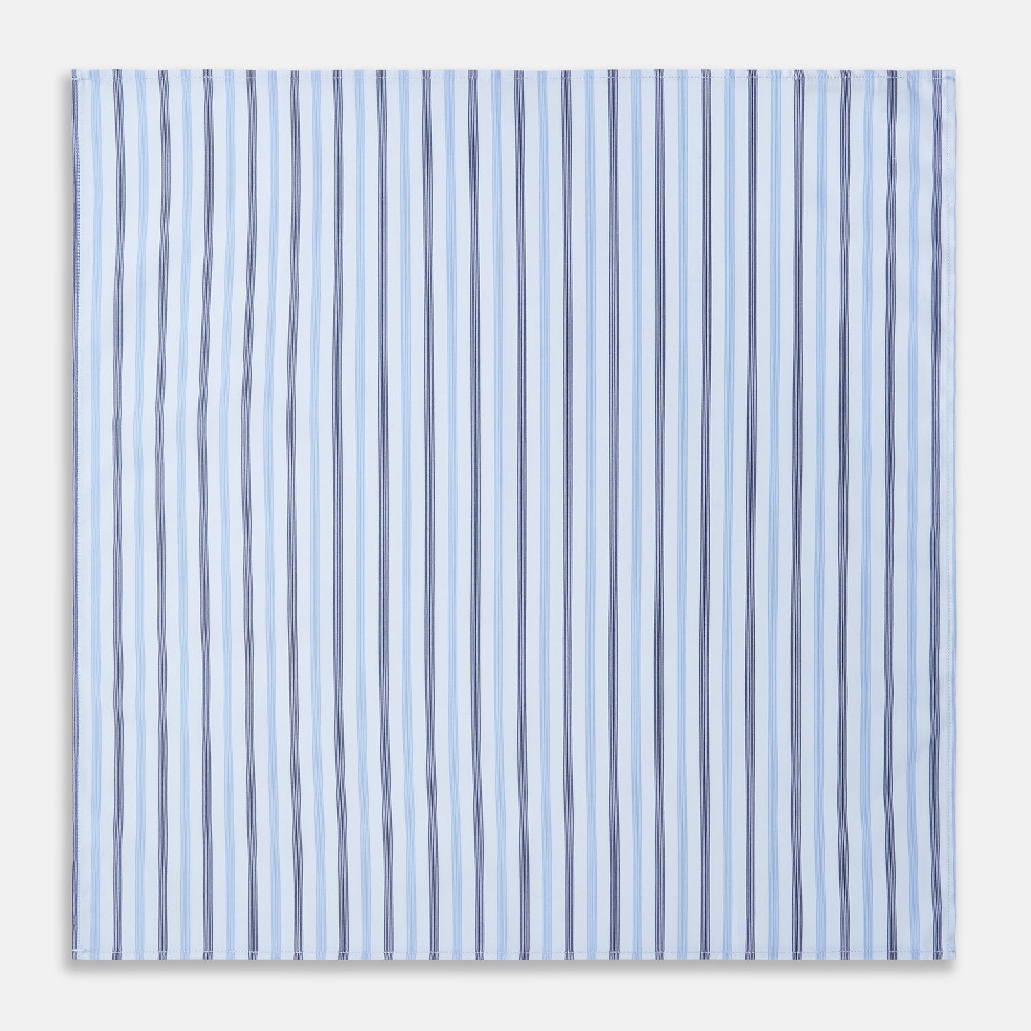 View 2 of product The Turnbull & Asser Blue Multi Stripe Cotton Handkerchief is shown flat against a white background, with one corner folded to reveal its reverse side. It features horizontal and vertical blue and white stripes on luxury cotton.