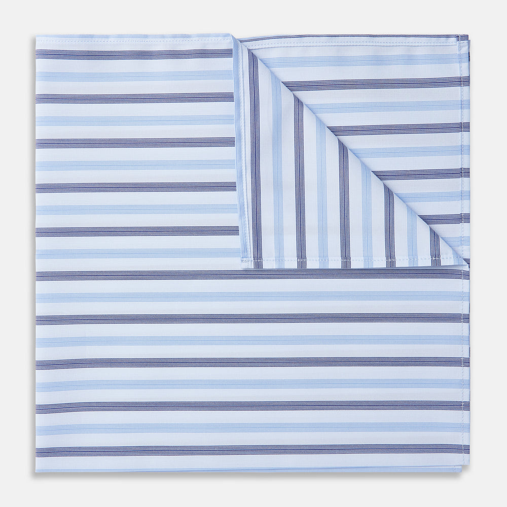 The Turnbull & Asser Blue Multi Stripe Cotton Handkerchief is shown flat against a white background, with one corner folded to reveal its reverse side. It features horizontal and vertical blue and white stripes on luxury cotton.