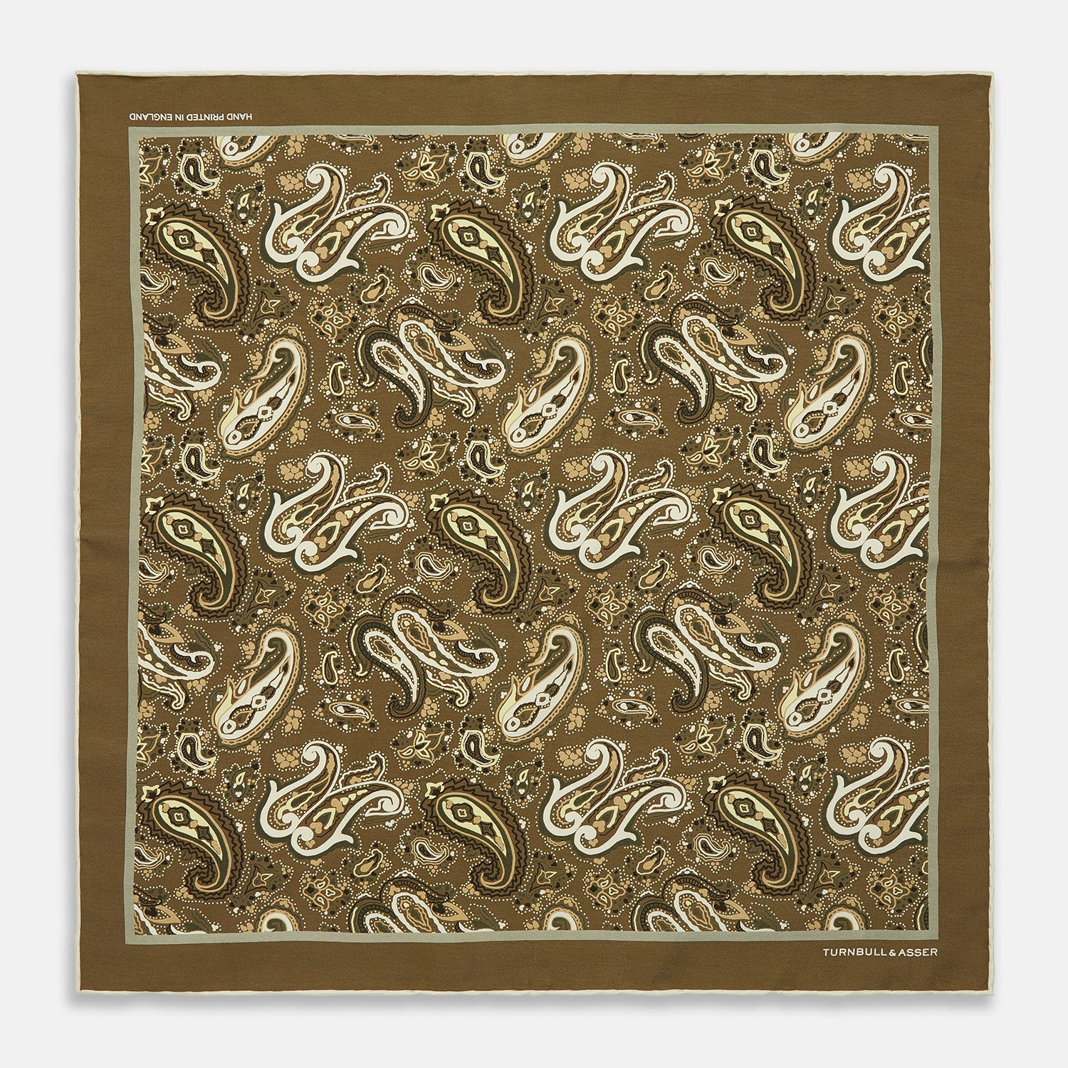 View 1 of product A green and lemon silk pocket square featuring a blossoming paisley pattern with a solid edge. “Turnbull & Asser” is inscribed in one corner; expertly crafted in England.