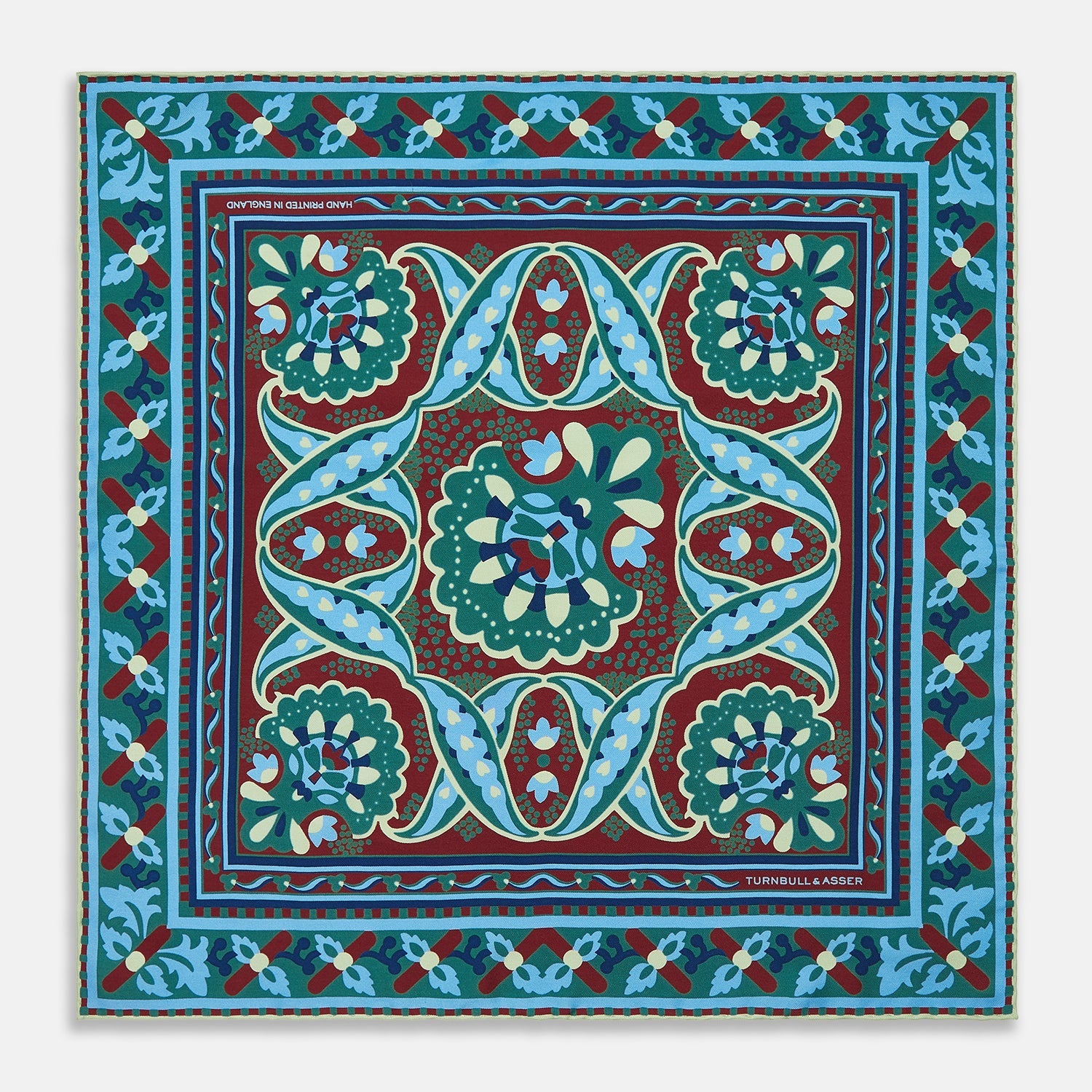 View 1 of product The Aqua and Burgundy Baroque Silk Pocket Square by Turnbull & Asser is crafted in England, featuring an intricate symmetrical pattern in teal, blue, red, and cream with ornate motifs framed by decorative borders.