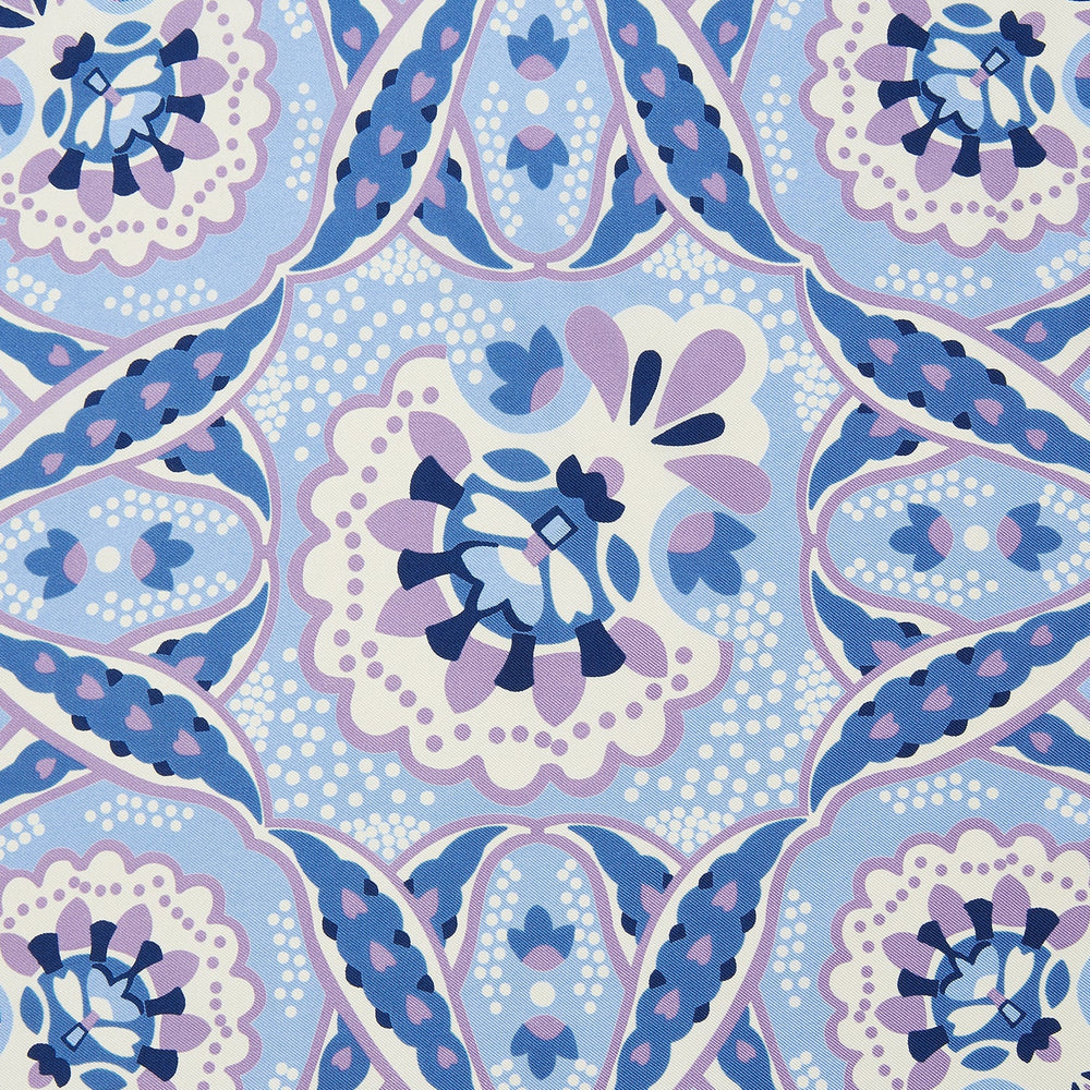 The Pale Blue and Lilac Baroque Silk Pocket Square by Turnbull & Asser features intricate geometric and floral patterns in blue, lilac, and white with a floral border and the brand name printed in one corner.