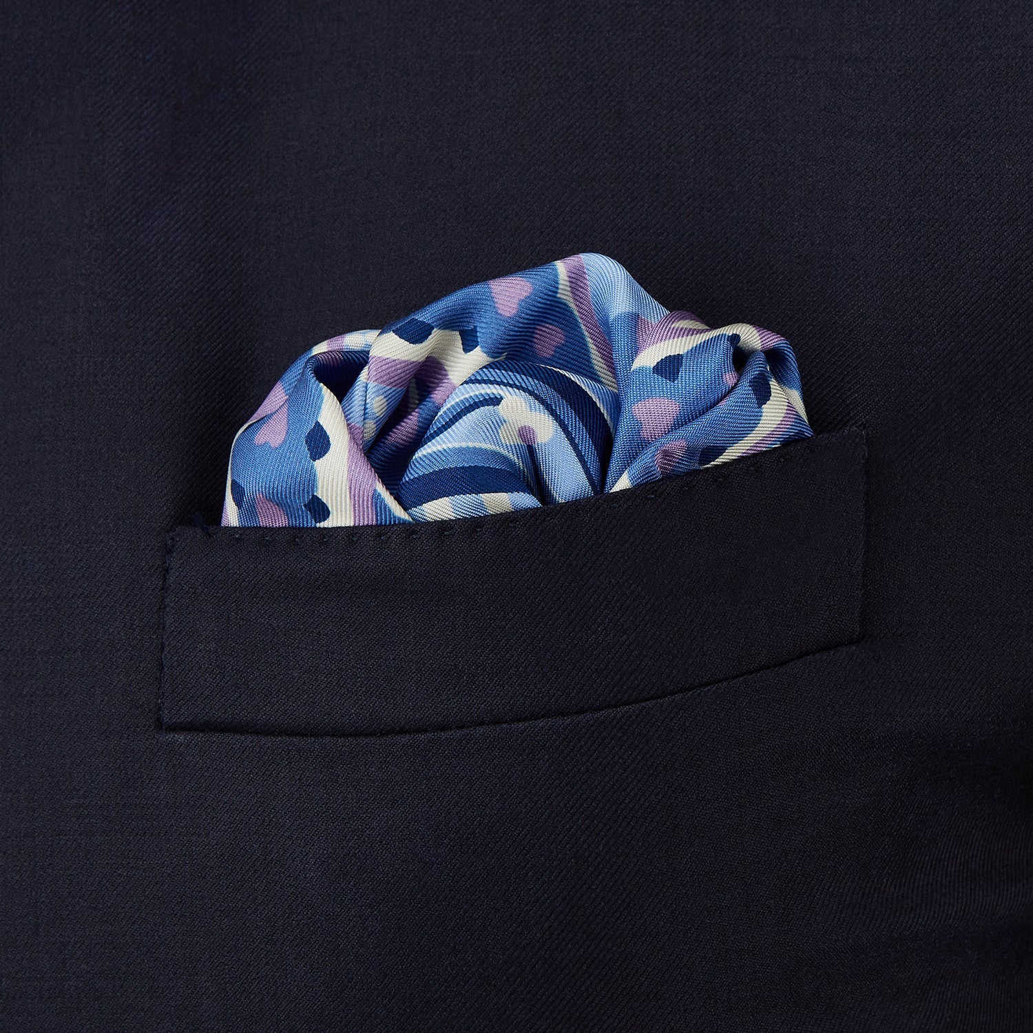 View 2 of product The Pale Blue and Lilac Baroque Silk Pocket Square by Turnbull & Asser features intricate geometric and floral patterns in blue, lilac, and white with a floral border and the brand name printed in one corner.