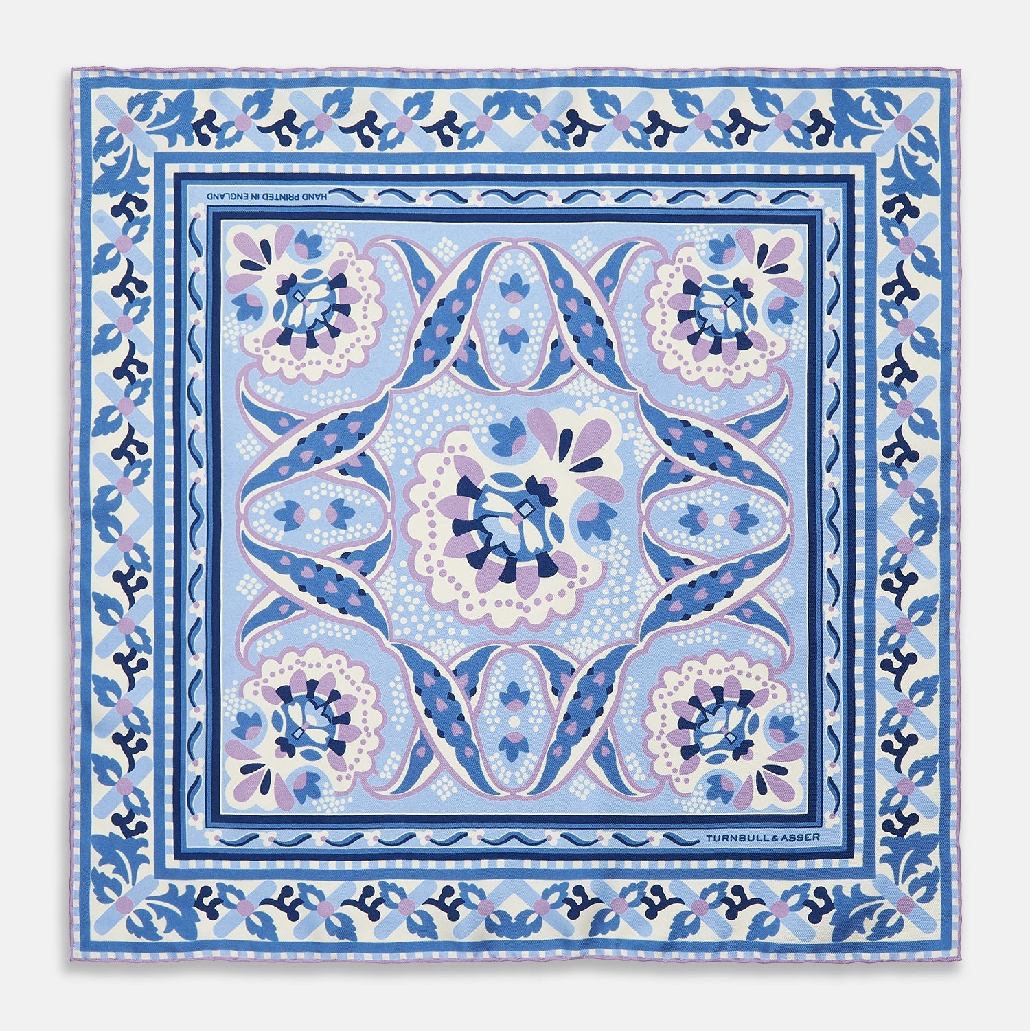 View 1 of product The Pale Blue and Lilac Baroque Silk Pocket Square by Turnbull & Asser features intricate geometric and floral patterns in blue, lilac, and white with a floral border and the brand name printed in one corner.