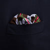View 3 of product The Turnbull & Asser Green and Red Checked Chess Board Silk Pocket Square features brown, green, red, and white stripes with a thin green border and the brand's name in the bottom right corner.