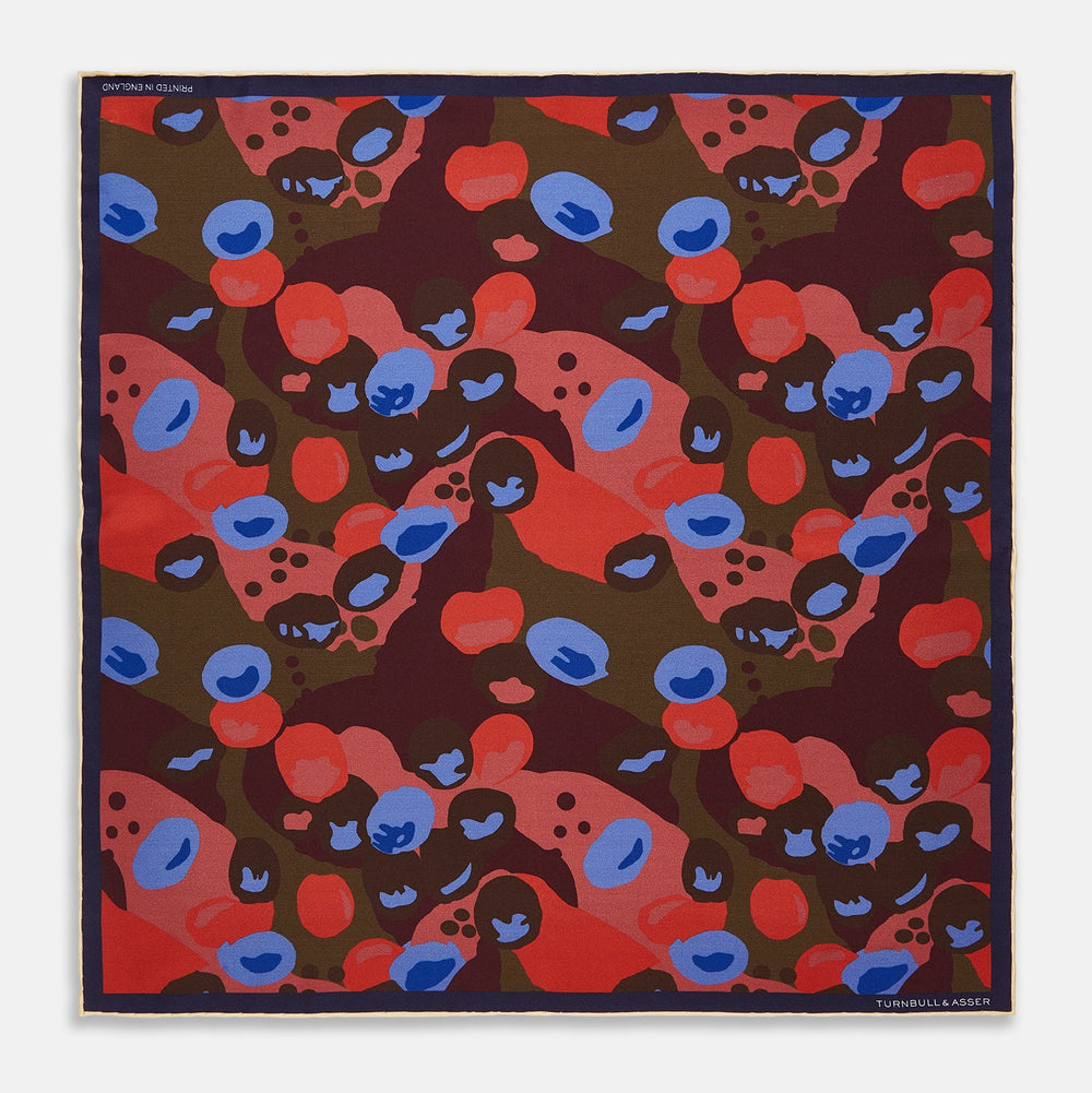 The Turnbull & Asser Green, Burgundy, and Pink Abstract Olives Silk Pocket Square features an abstract olive pattern with bold colors, a border, and corner text. Made in England.