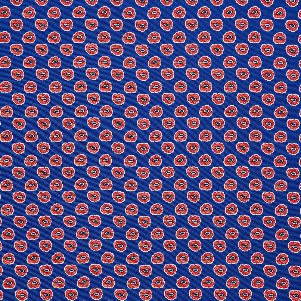 The Blue and Red Paisley Tiles Silk Pocket Square by Turnbull & Asser features a blue background, red and white paisley border, central repeating circular patterns, and “Turnbull & Asser” in one corner. Made in England.