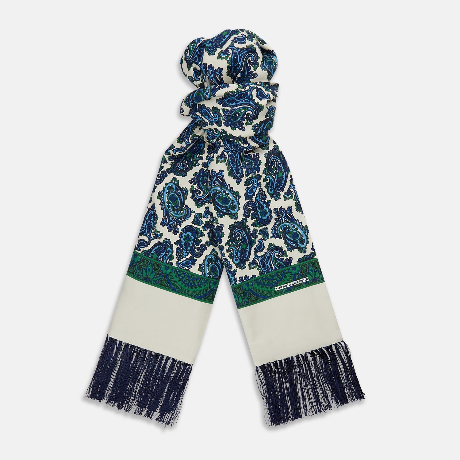 View 1 of product The Turnbull & Asser Green and Blue Paisley Silk Scarf features a blue and green paisley print on white, a solid cream section, a green stripe, and navy fringed ends.