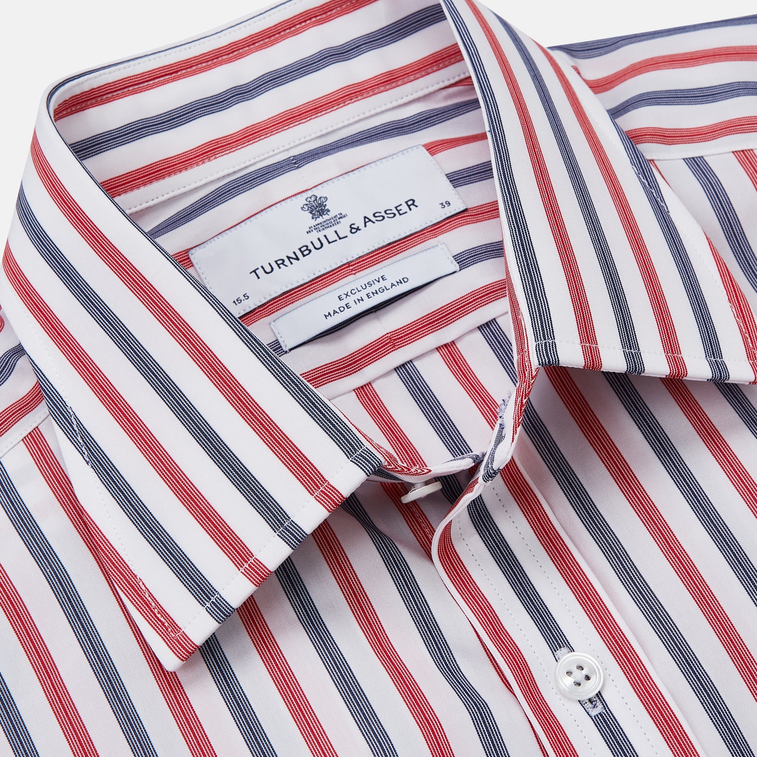 View 3 of product The Turnbull & Asser Red and Blue Stripe Cotton Regular Fit Whitby Shirt is a long-sleeve button-up featuring vibrant red and blue stripes on white, with a collar and buttoned cuffs, shown on a plain white surface.
