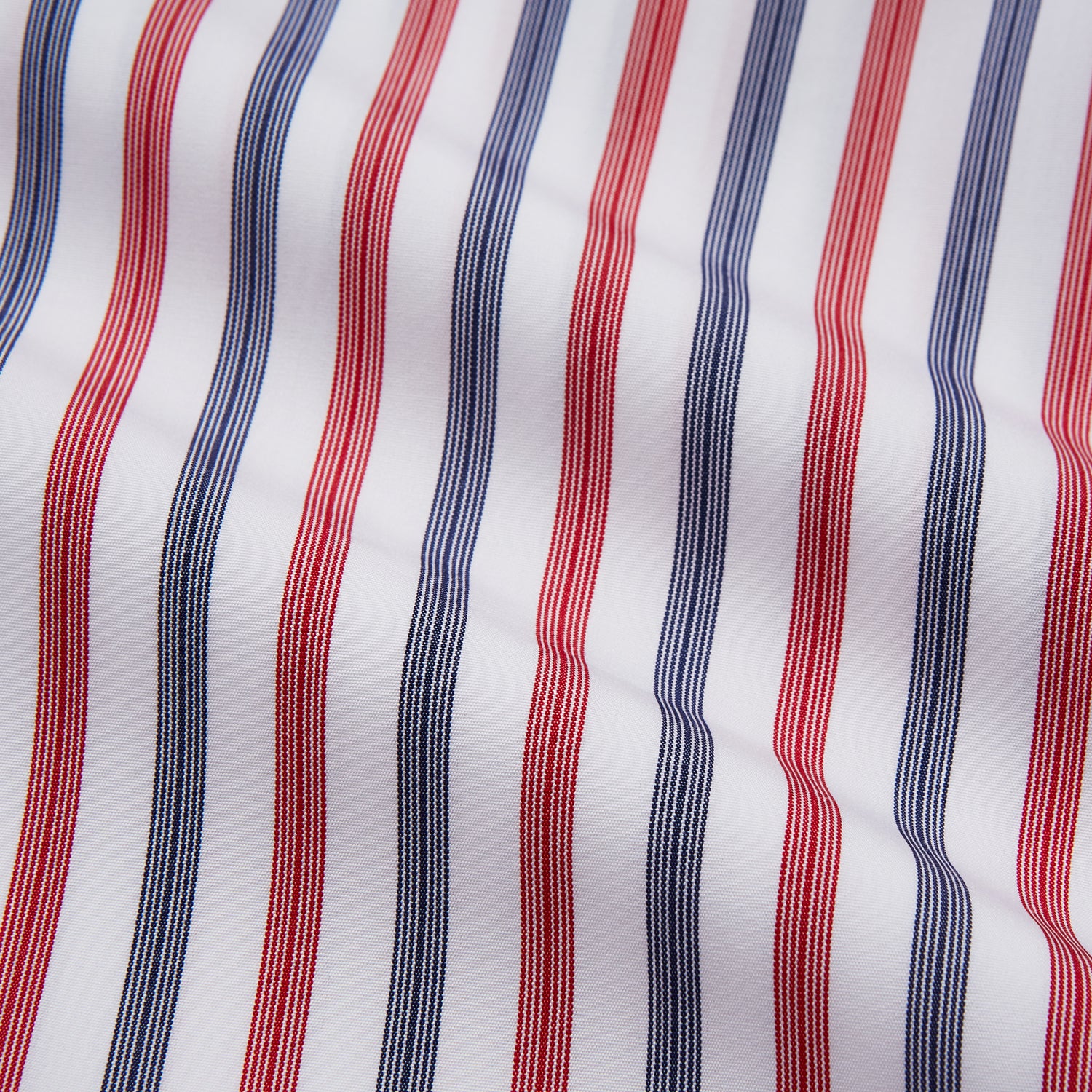 View 2 of product The Turnbull & Asser Red and Blue Stripe Cotton Regular Fit Whitby Shirt is a long-sleeve button-up featuring vibrant red and blue stripes on white, with a collar and buttoned cuffs, shown on a plain white surface.