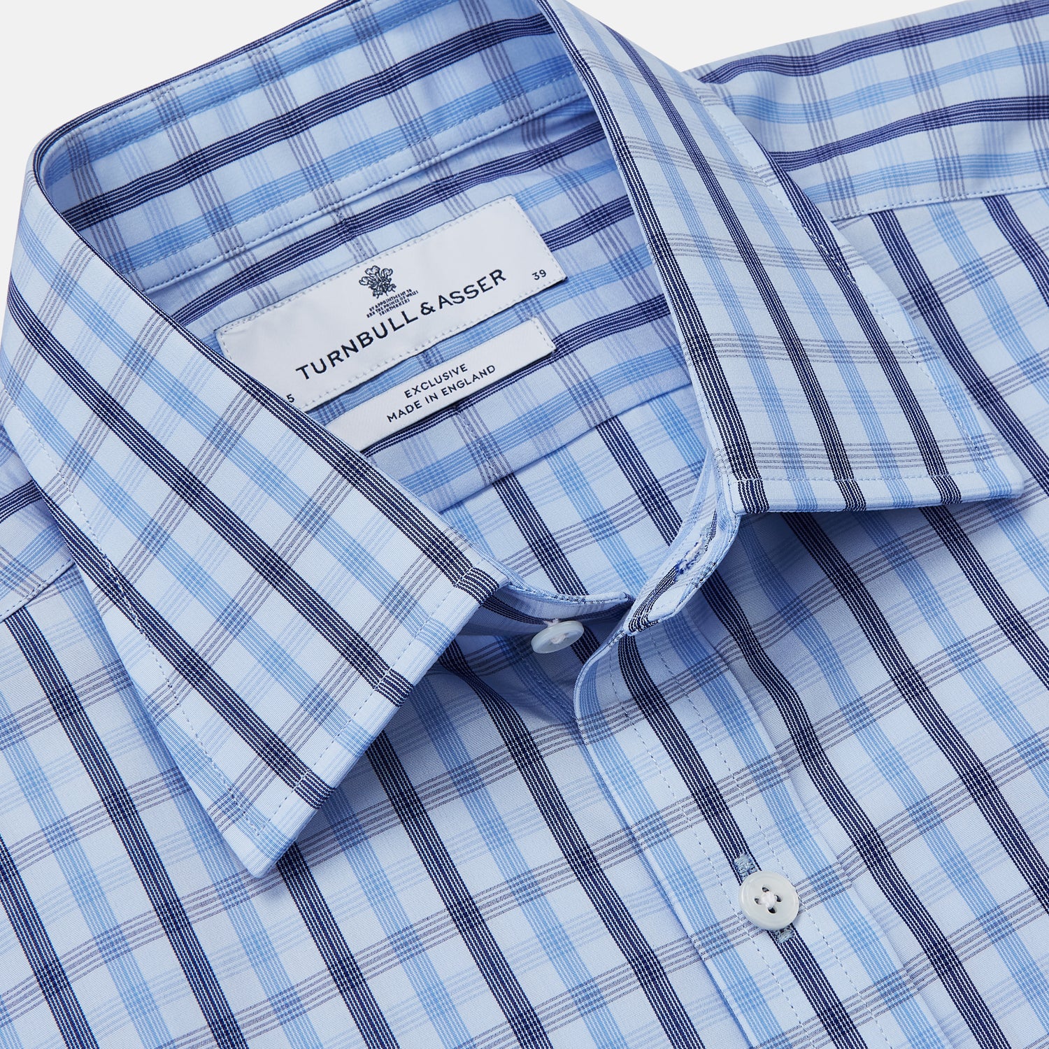 View 2 of product The Turnbull & Asser Light Blue and Navy Check Cotton Regular Fit Mayfair Shirt features a T&A collar and button-up long sleeves, displayed laid flat on a white background.