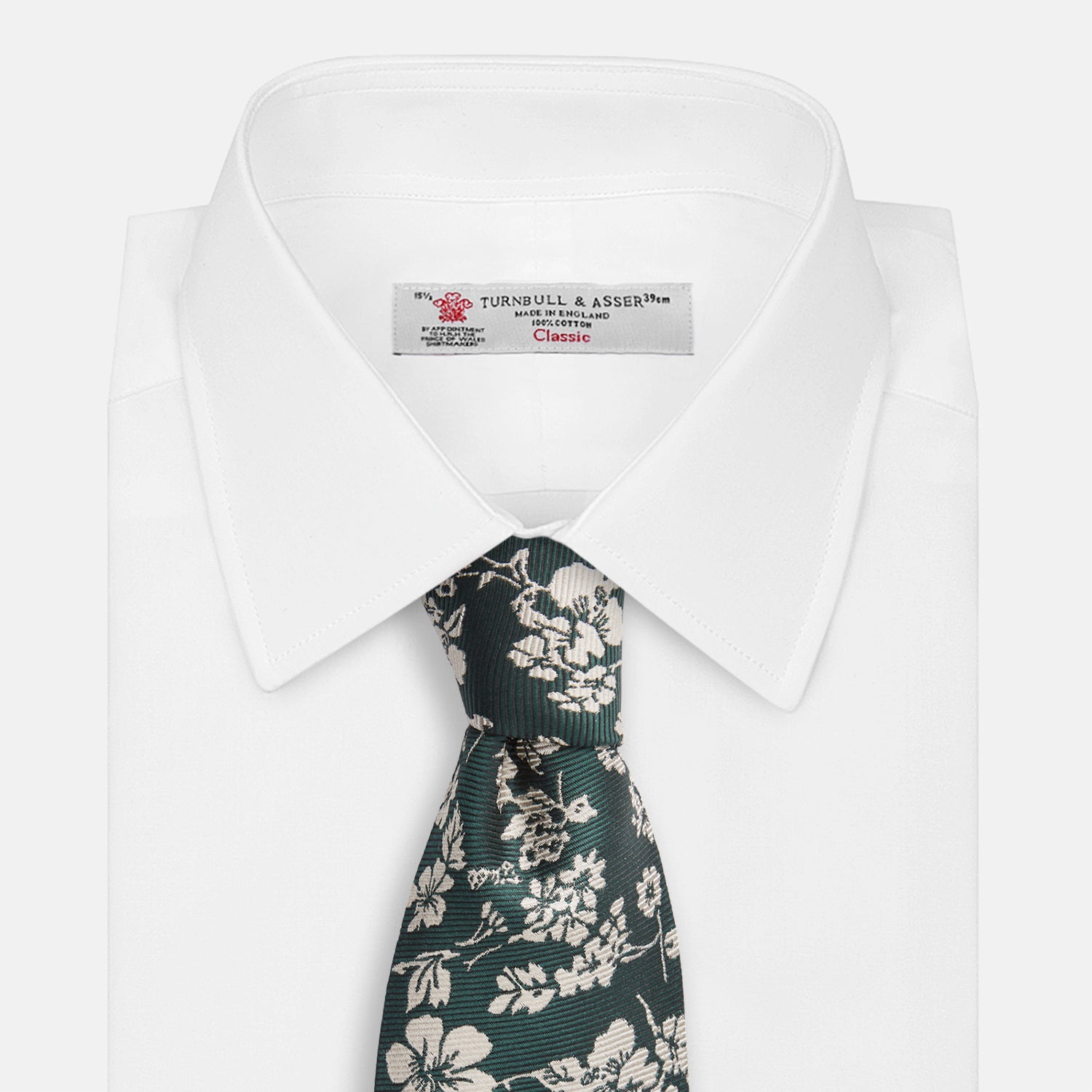 View 4 of product The Turnbull & Asser Dark Green Floral Garden Silk Tie features an elegant white floral pattern on dark green silk, shown rolled against a plain white background.